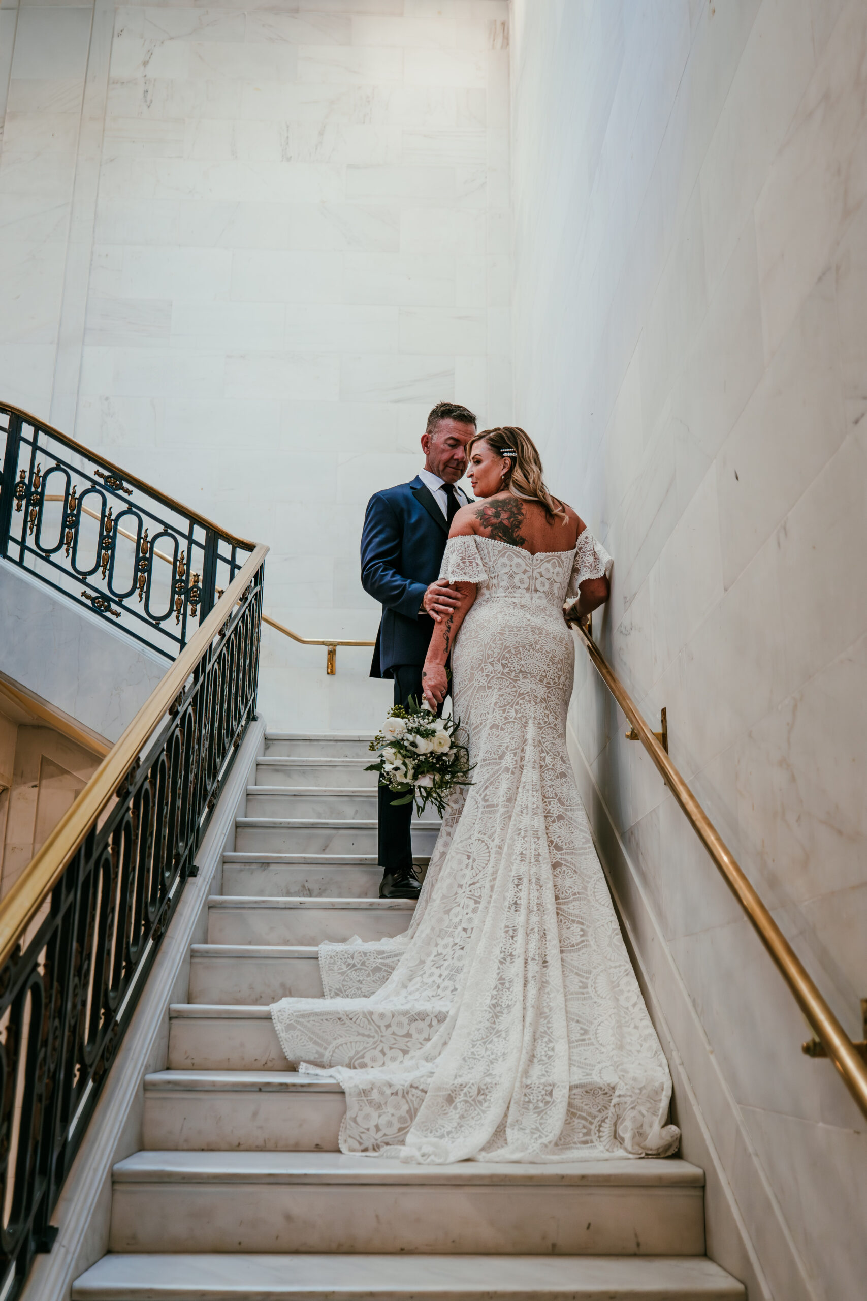 Bride and groom sharing an intimate moment on the marble staircase at San Francisco City Hall during their elopement, photographed by a san francisco elopement photographer.