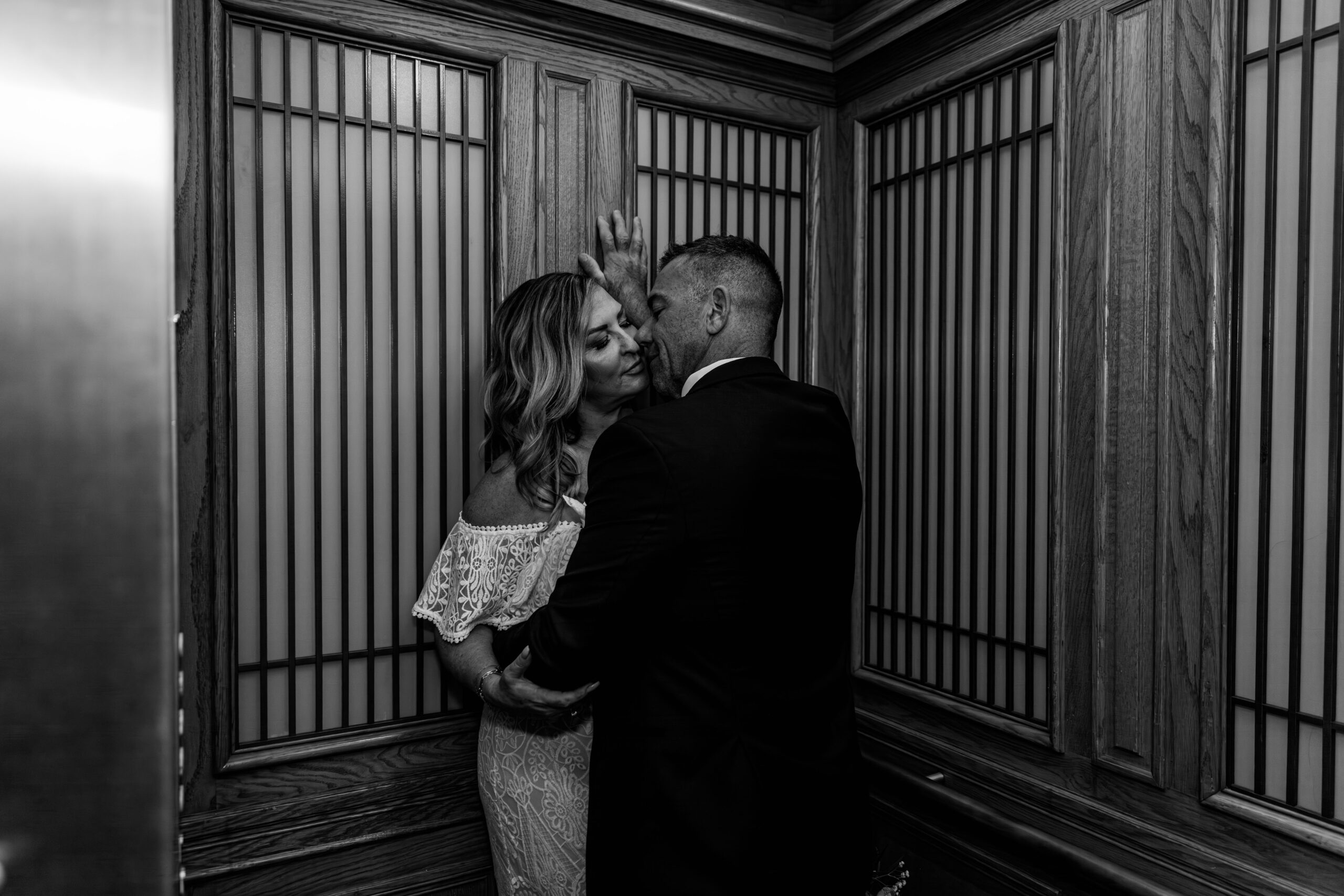 Black and white photo of the couple sharing an intimate moment inside the historic elevator at San Francisco City Hall during their elopement, captured by a san francisco elopement photographer.