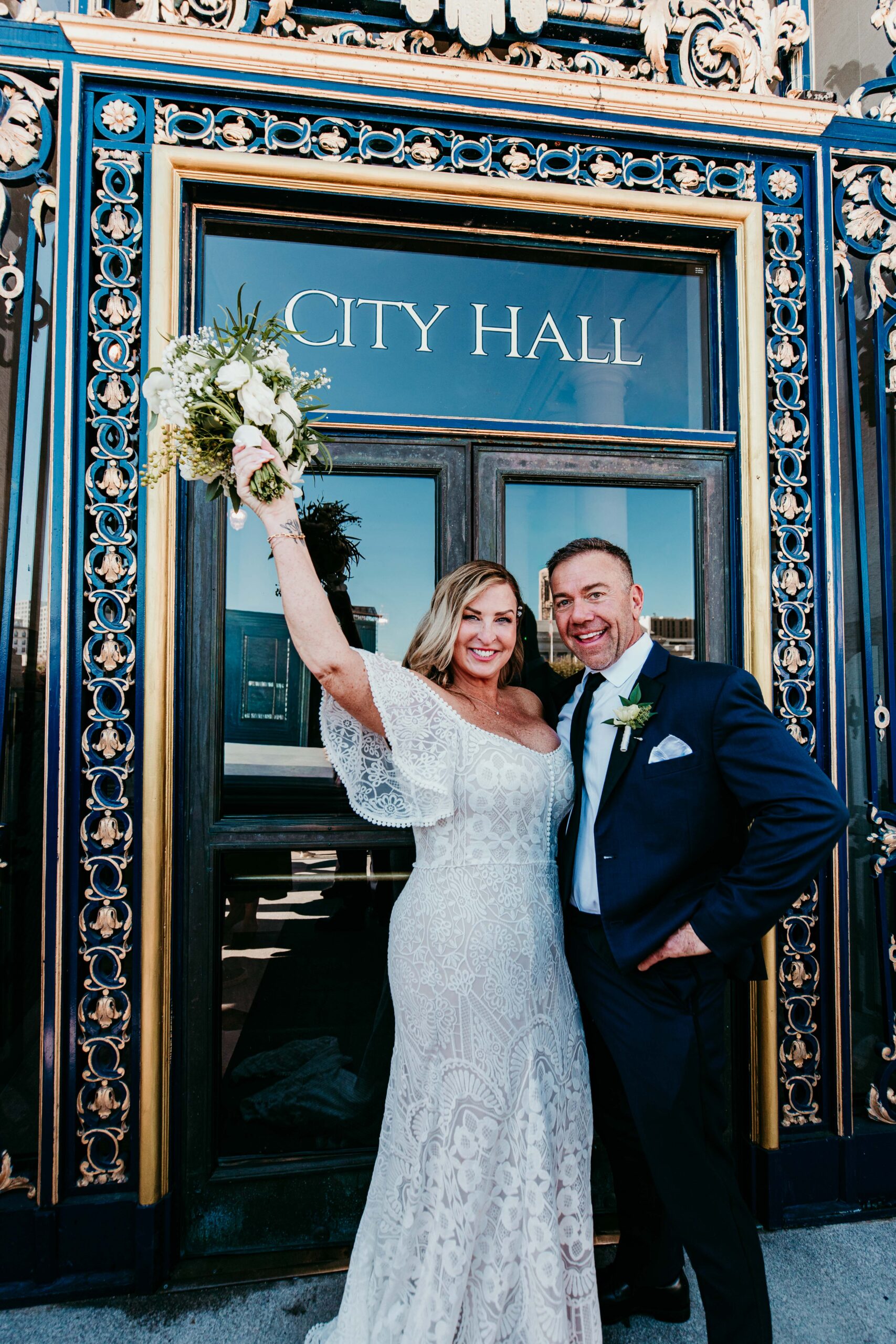 Bride and groom celebrating outside the entrance of San Francisco City Hall after their elopement, photographed by a san francisco elopement photographer.