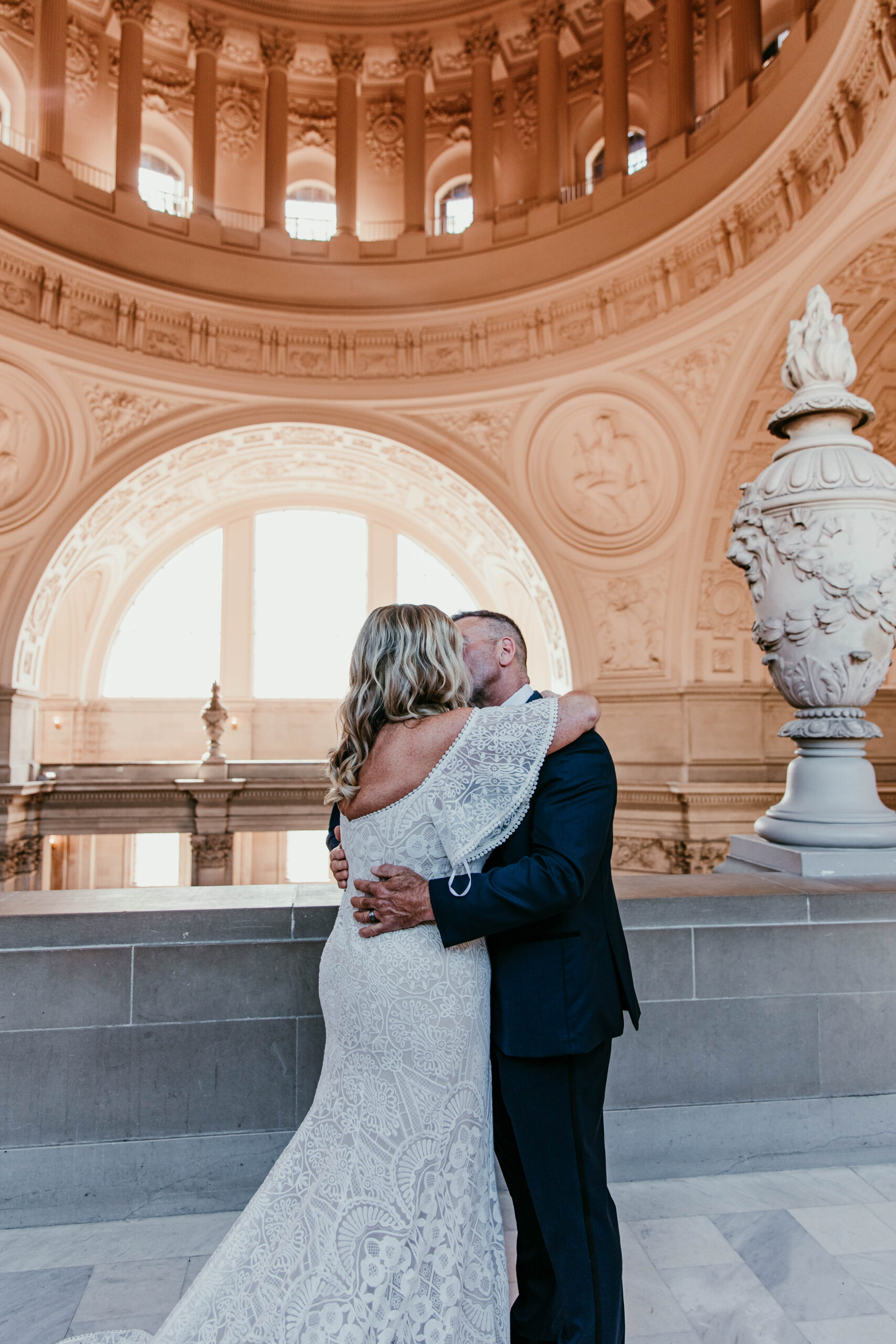 Bride and groom sharing their first kiss on the Fourth Floor balcony during their San Francisco City Hall elopement, photographed by a san francisco elopement photographer.