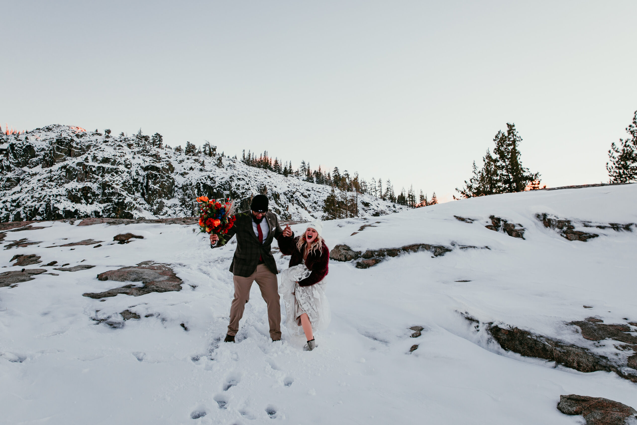 Couple laughing and playing in the snow during a winter Lake Tahoe elopement in the mountains
