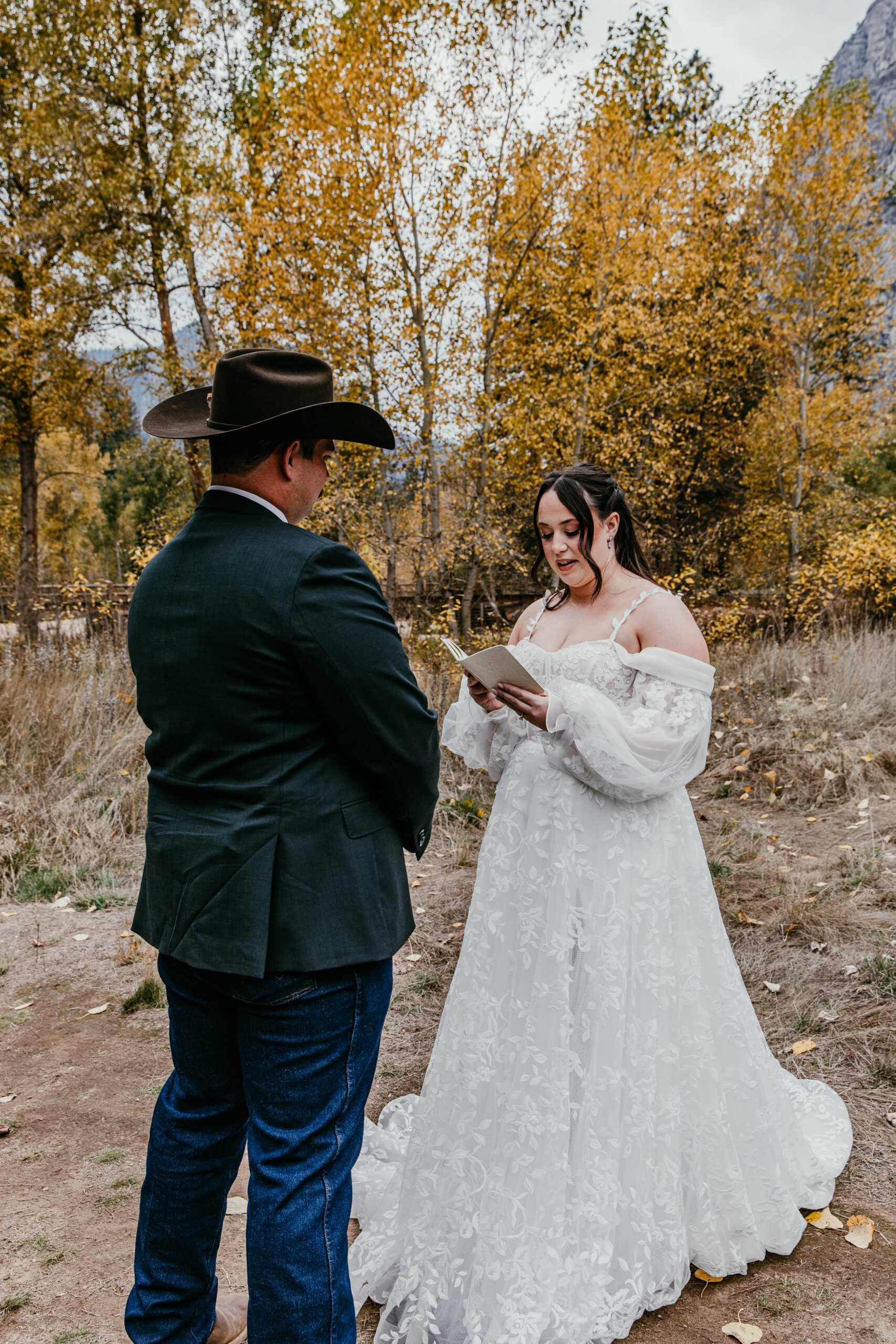 Bride reading vows during a fall elopement ceremony, wearing a long sleeve lace elopement dress