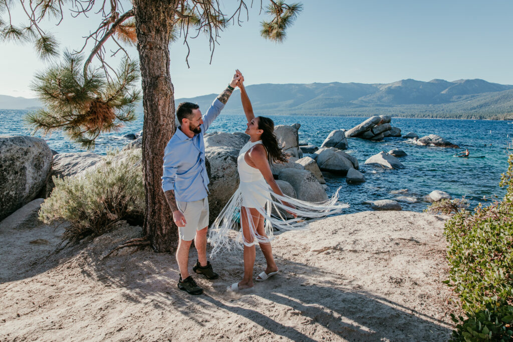 Couple spinning together during a beach elopement, bride wearing a short and lightweight elopement dress near the shoreline