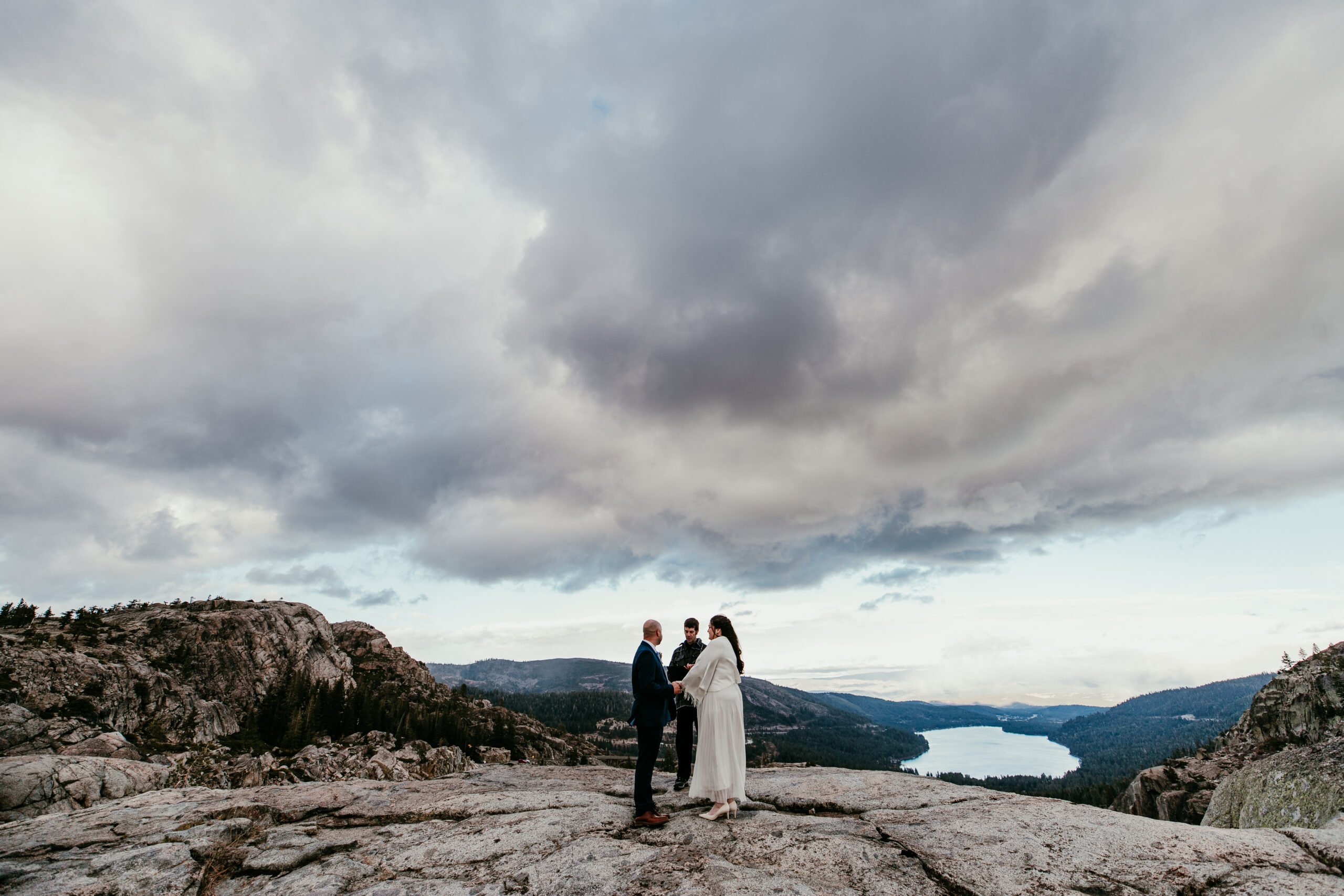 Small elopement ceremony on a rocky overlook with lake views and dramatic clouds