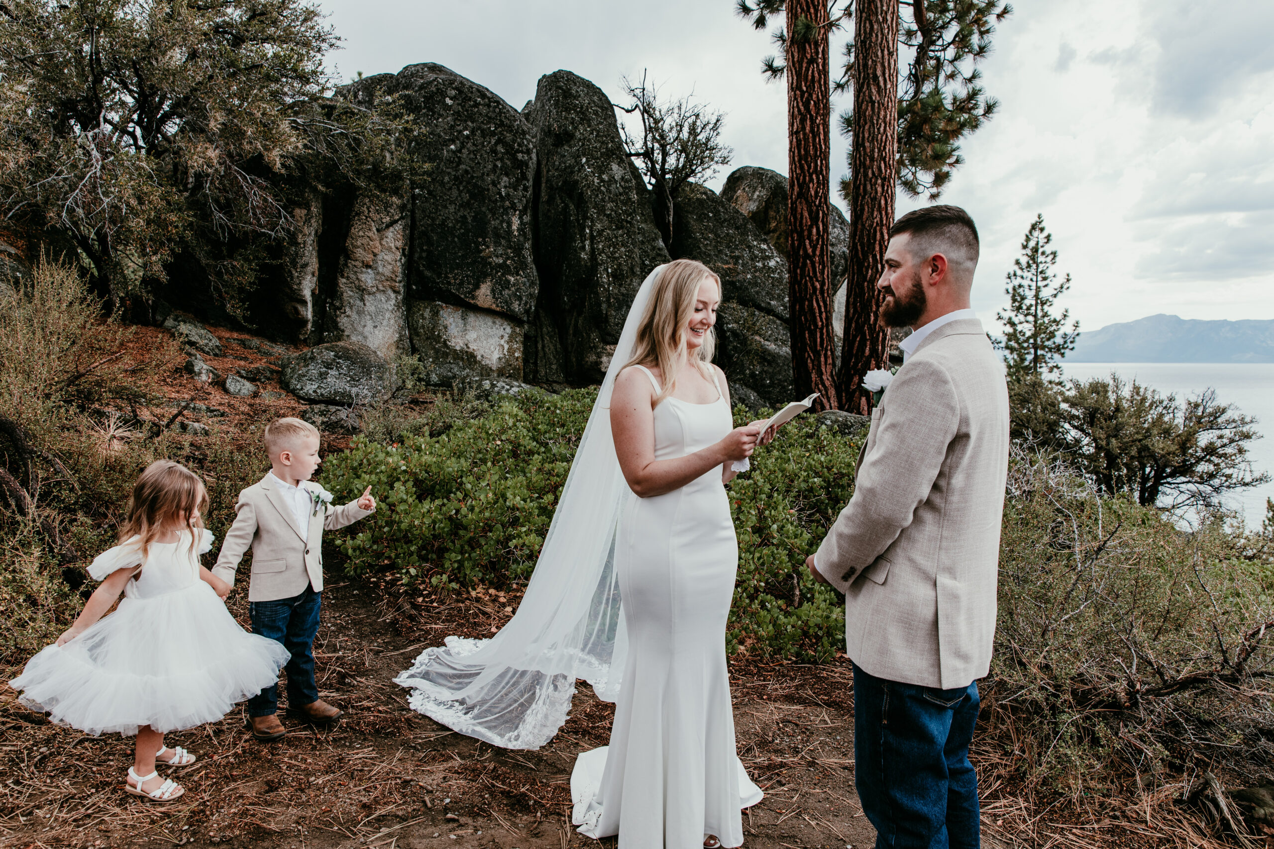 Couple getting married in Lake Tahoe during an intimate outdoor ceremony with their children nearby, surrounded by pine trees and granite boulders.