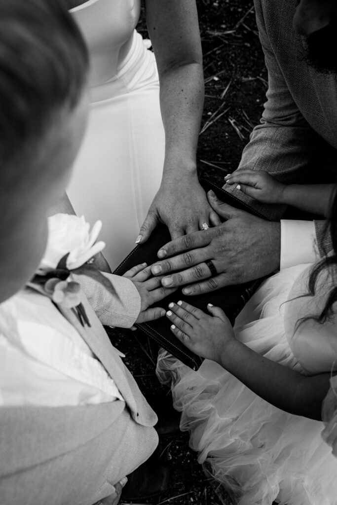 Family hands stacked together on Bible during intimate Lake Tahoe elopement ceremony