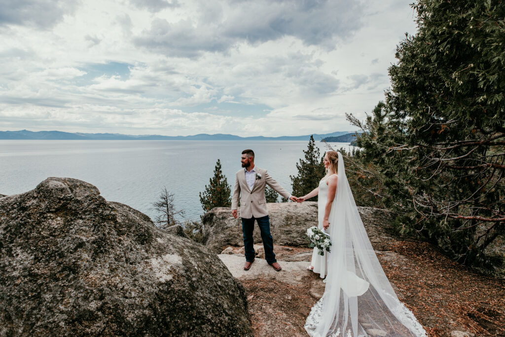 Couple holding hands on rocky overlook during Lake Tahoe blended family elopement