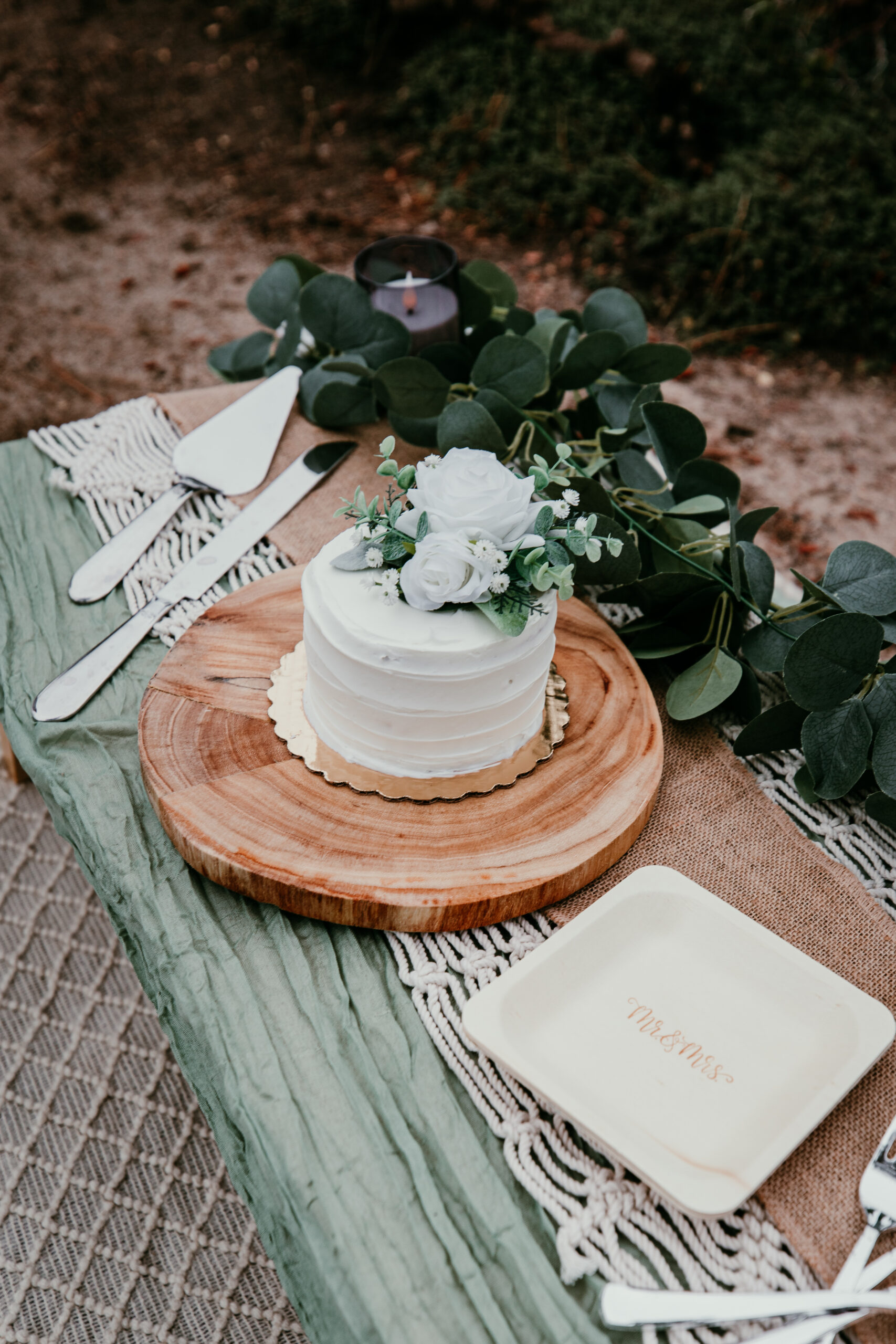 Small wedding cake and picnic setup detail with greenery and simple decor for an intimate celebration