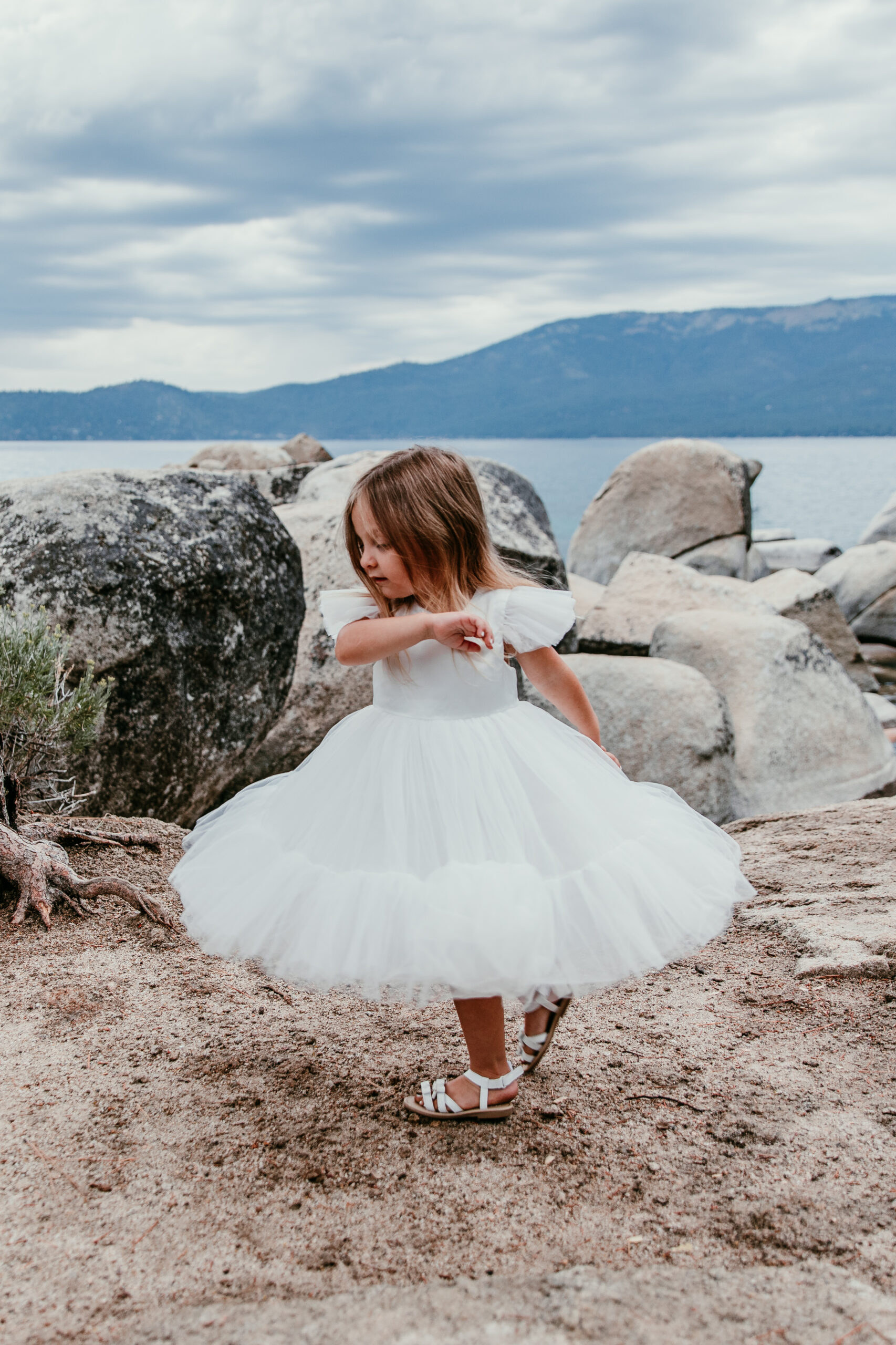 Little girl twirling on Lake Tahoe shoreline during blended family elopement