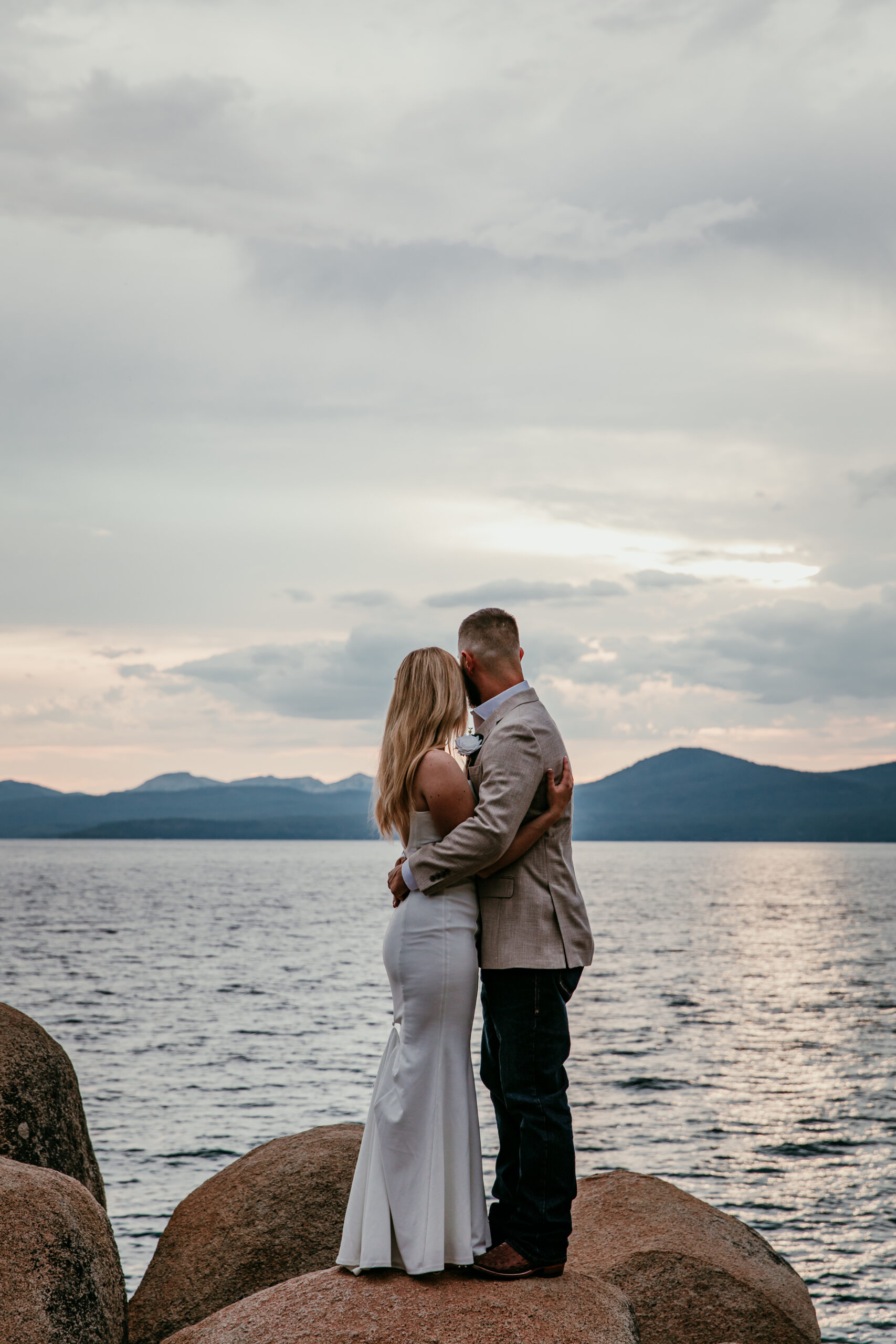 Lake Tahoe elopement couple embracing on rocky shoreline with mountain lake views in Northern California