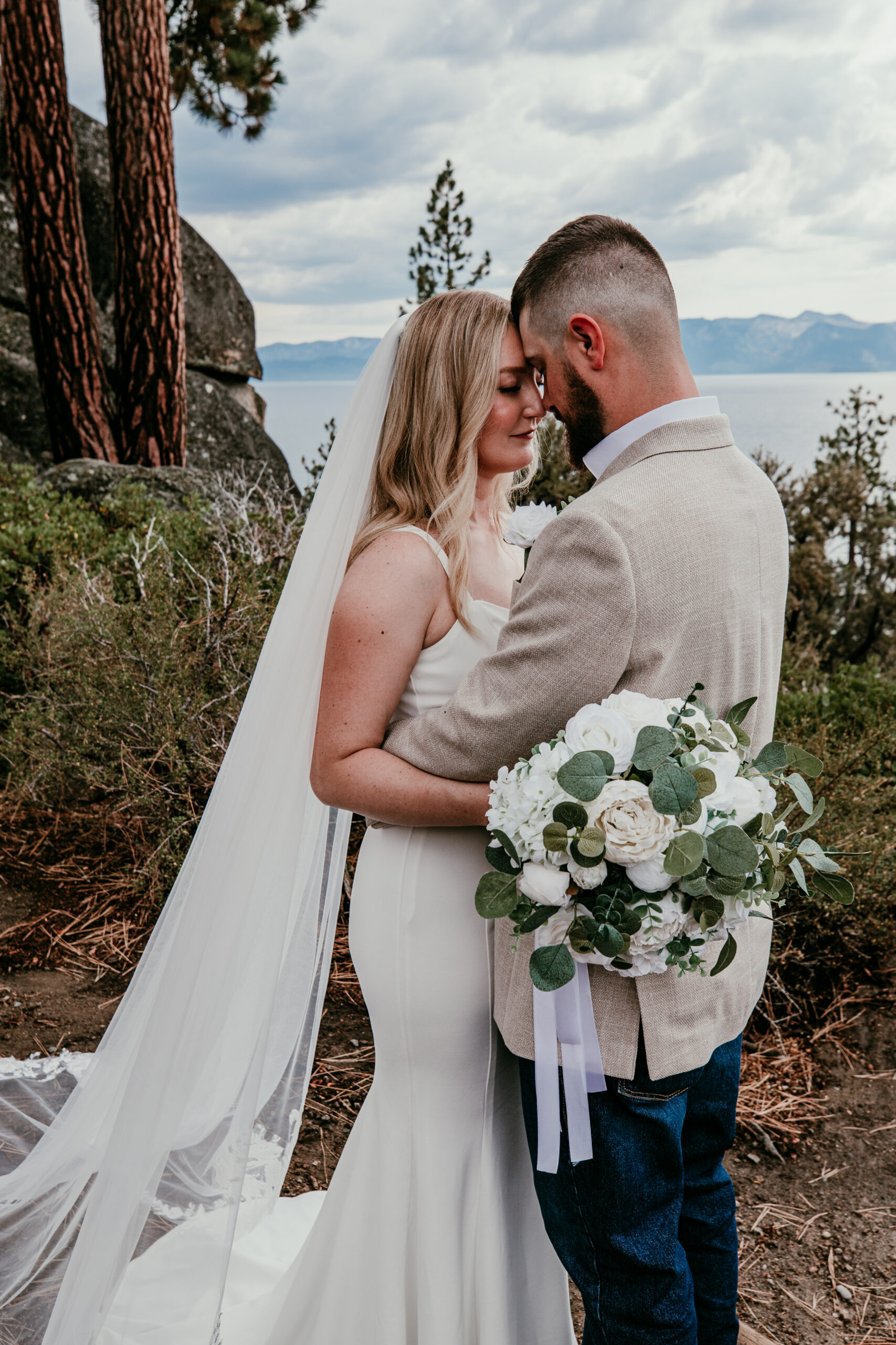 Bride holding white faux floral bouquet during Lake Tahoe blended family elopement at Logan Shoals Vista Point