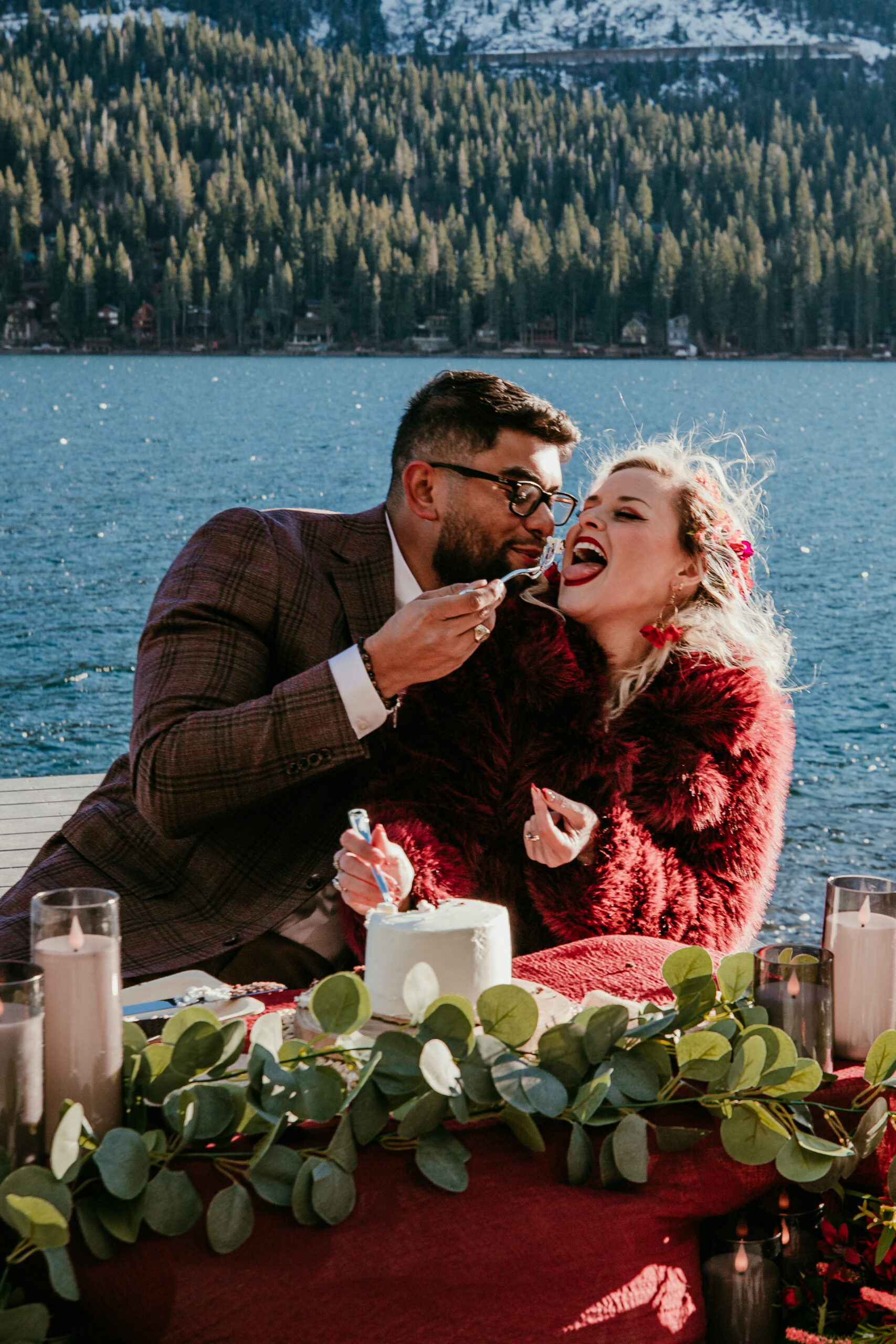Bride and groom laughing while sharing cake during their snowy Truckee winter elopement at Donner Lake.