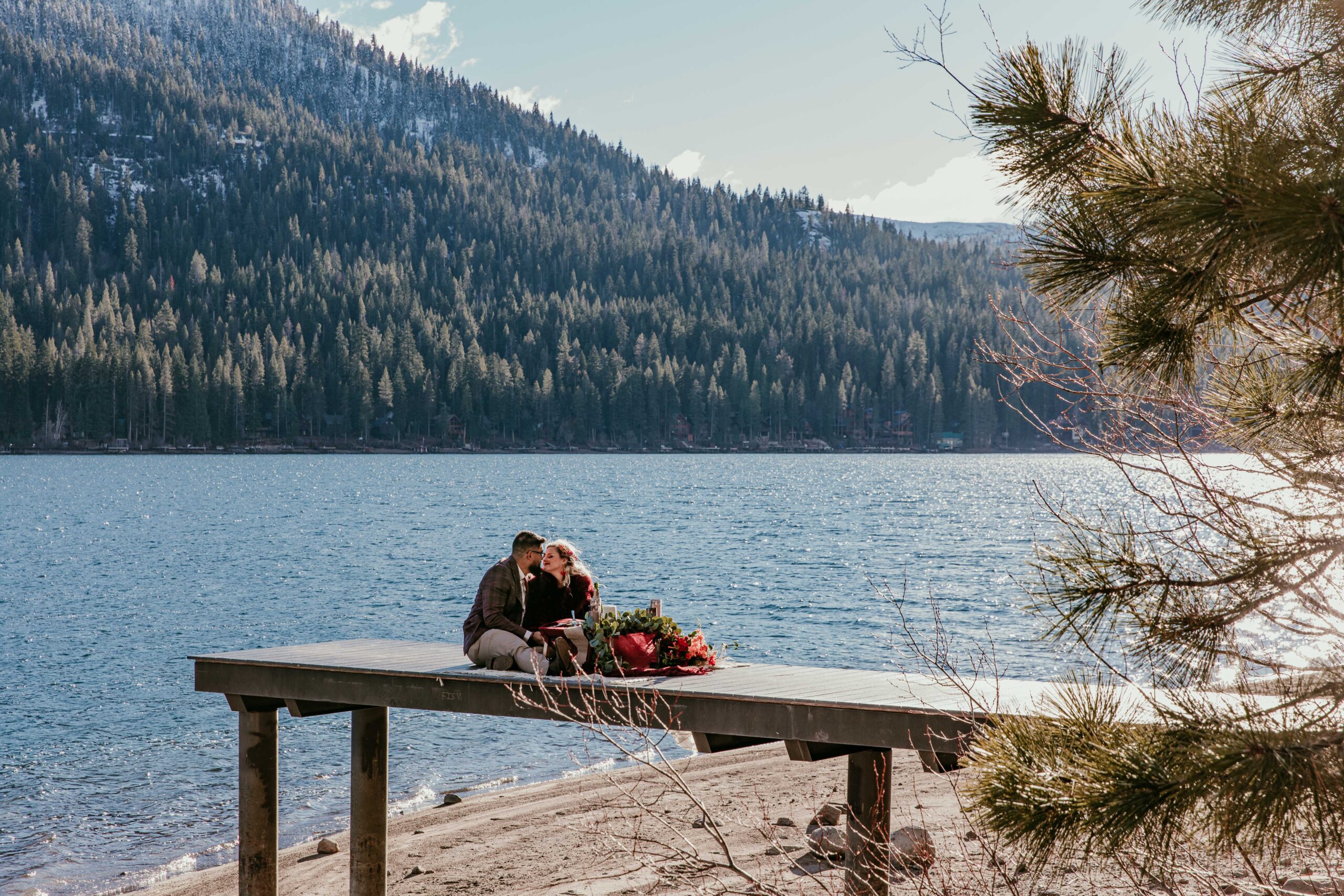 Wide portrait of couple celebrating their winter elopement on a dock at Donner Lake in Truckee, California.