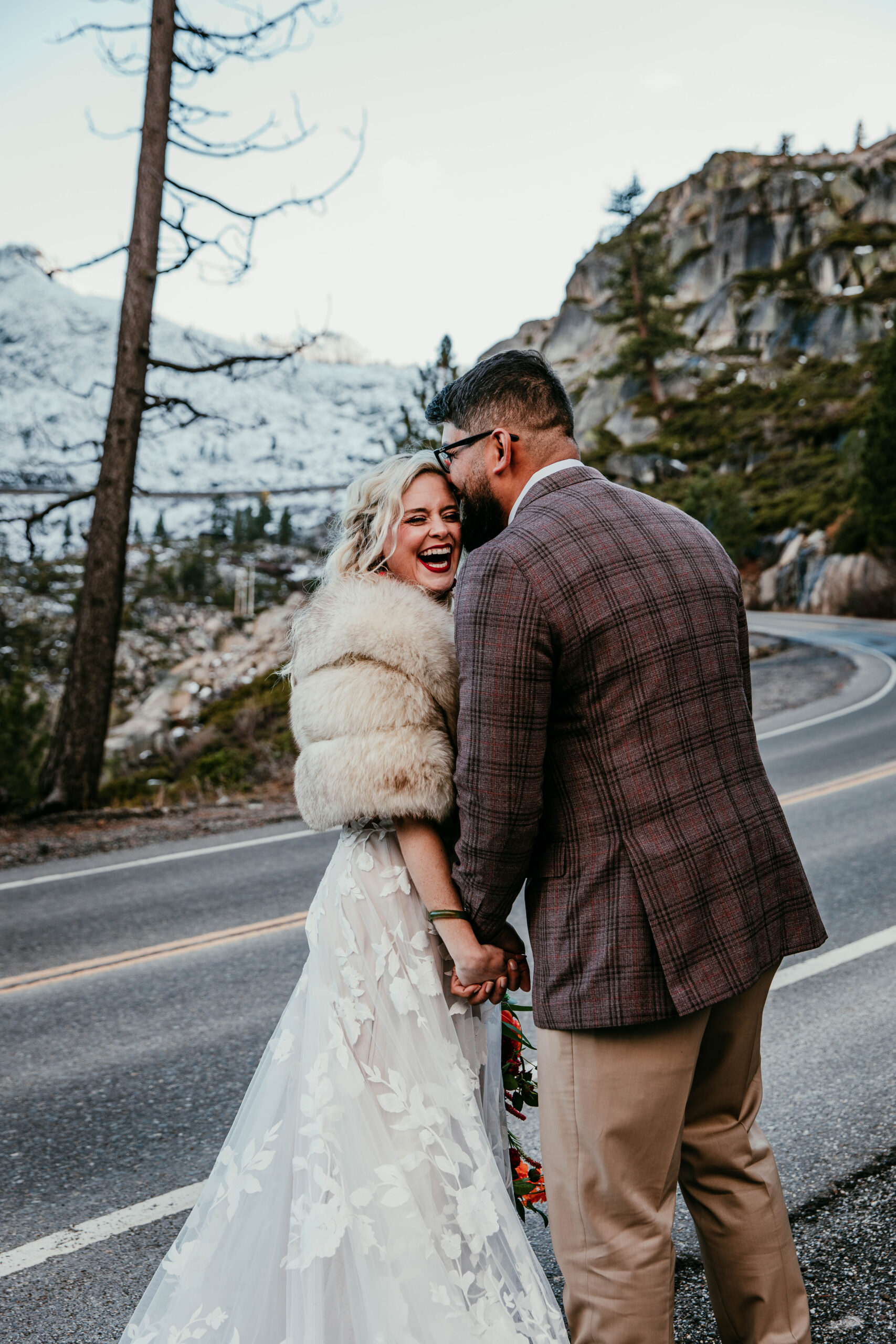 Couple laughing together on a mountain road during their Lake Tahoe elopement in winter