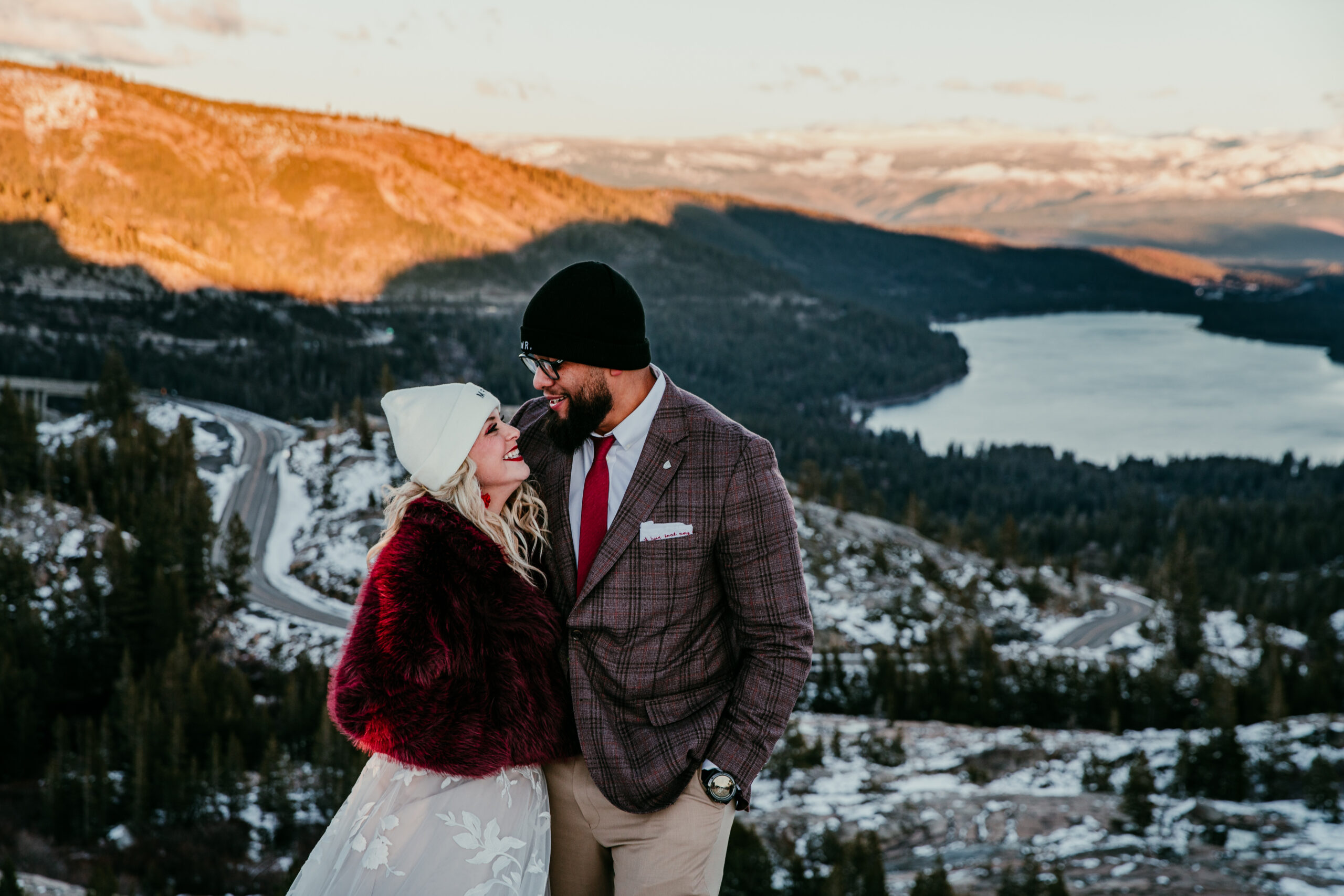 Bride and groom overlooking snow-covered mountains at Donner Summit during sunset in the Sierra Nevada.