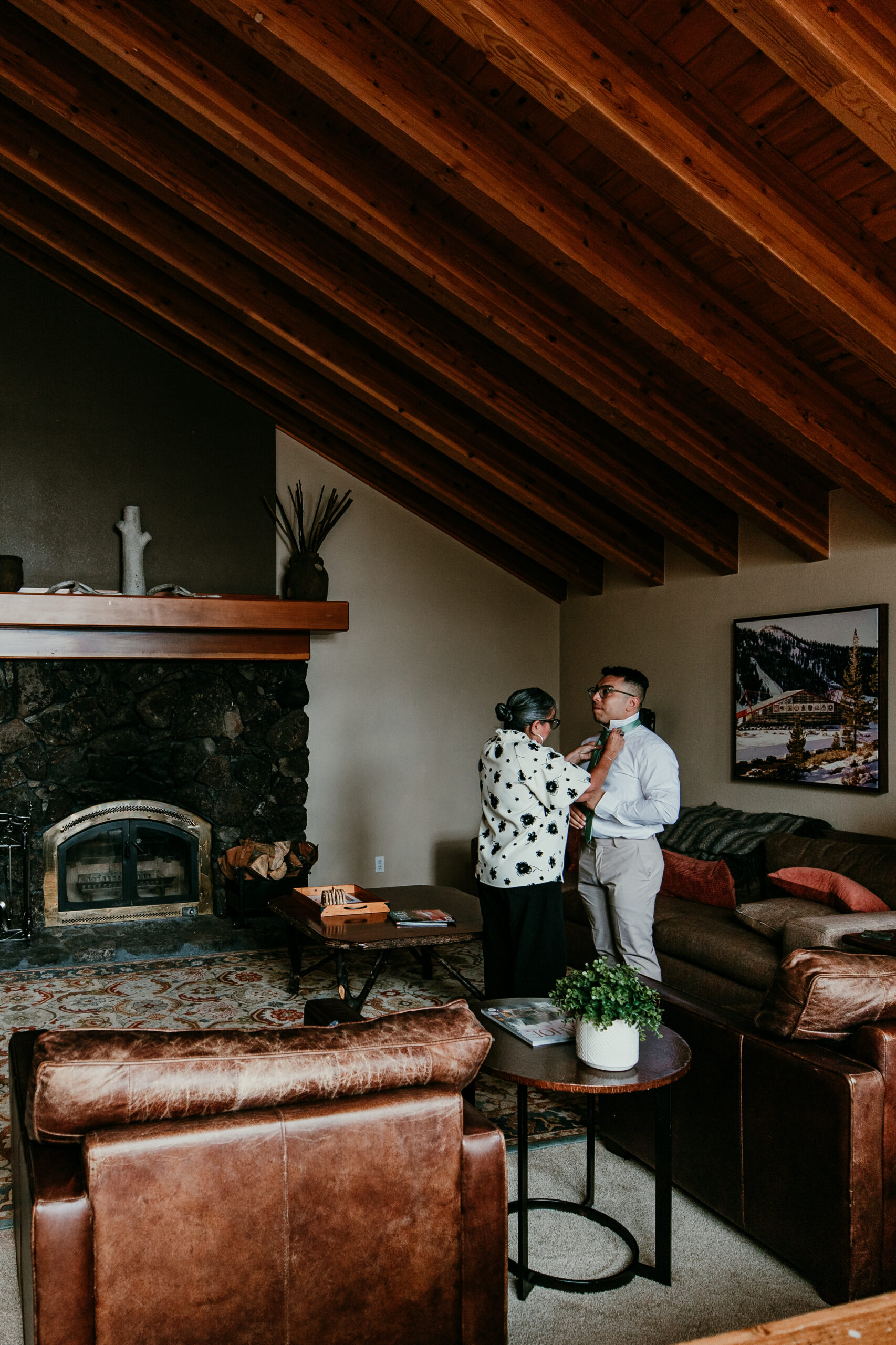 Groom getting ready inside a Lake Tahoe Airbnb as his mom helps adjust his tie before the elopement ceremony.