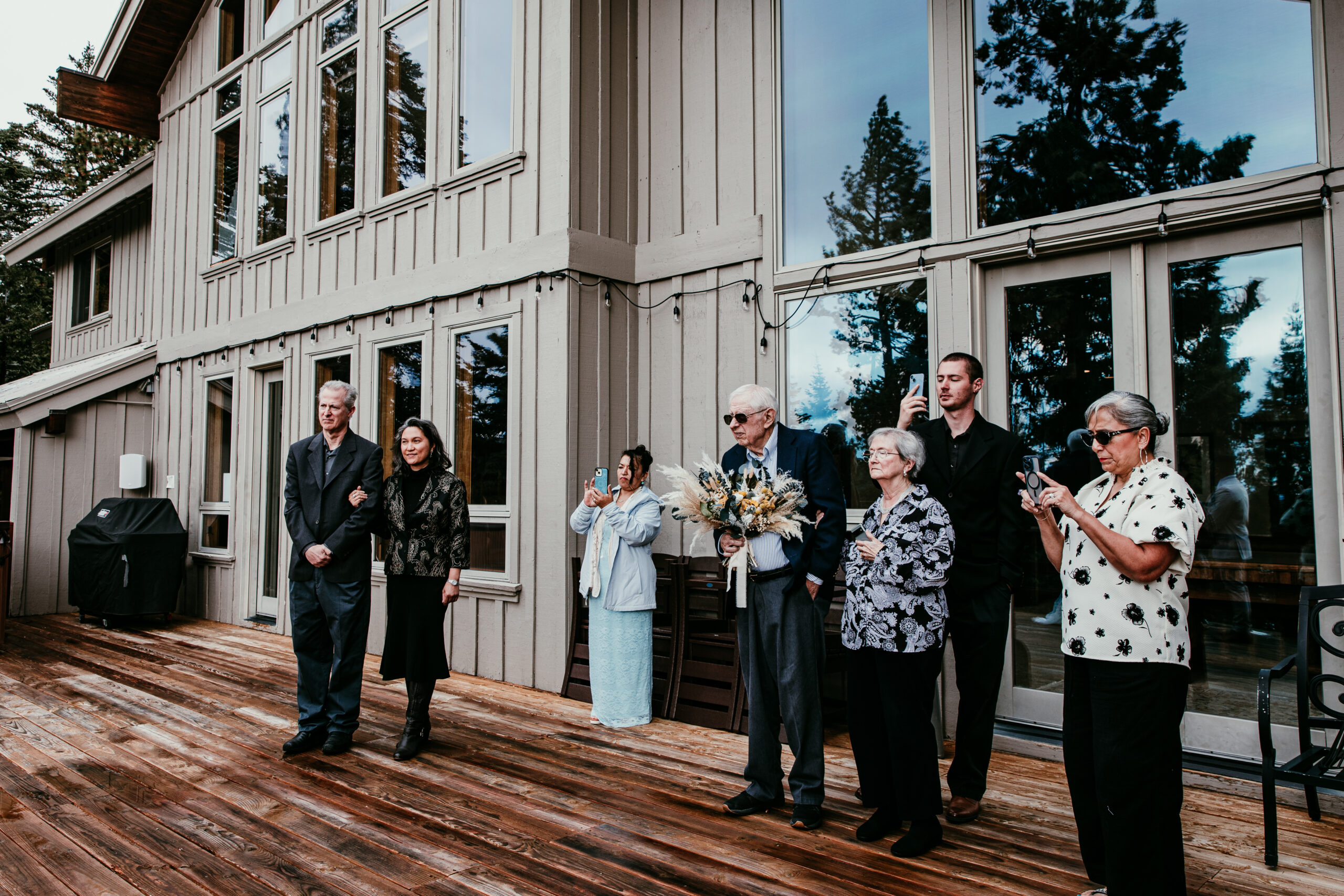Family members watching and taking photos during a small outdoor elopement ceremony at a Lake Tahoe Airbnb.