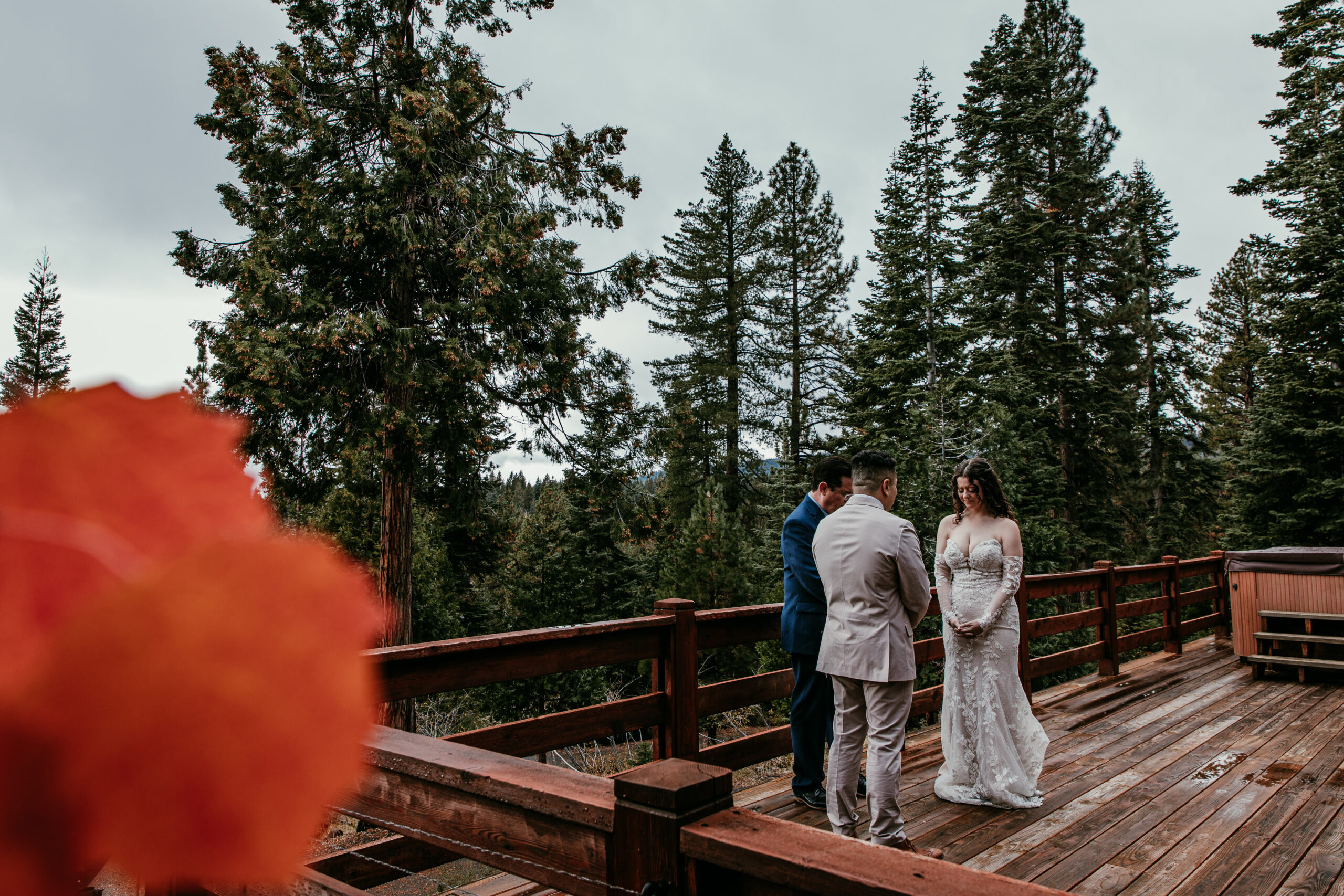 Bride and groom exchanging vows on a wooden deck with fall leaves and pine trees overlooking Lake Tahoe.