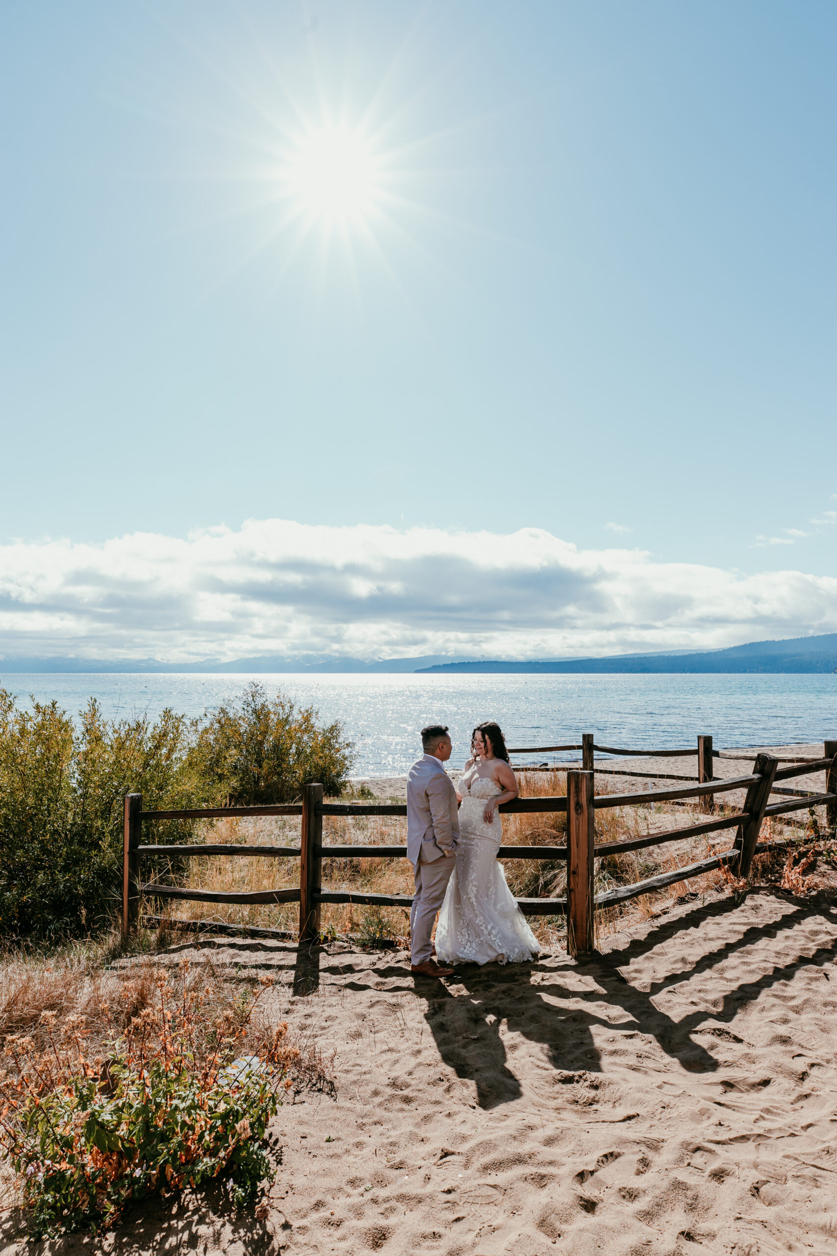 Bride and groom sharing a quiet moment near a wooden fence overlooking Lake Tahoe.