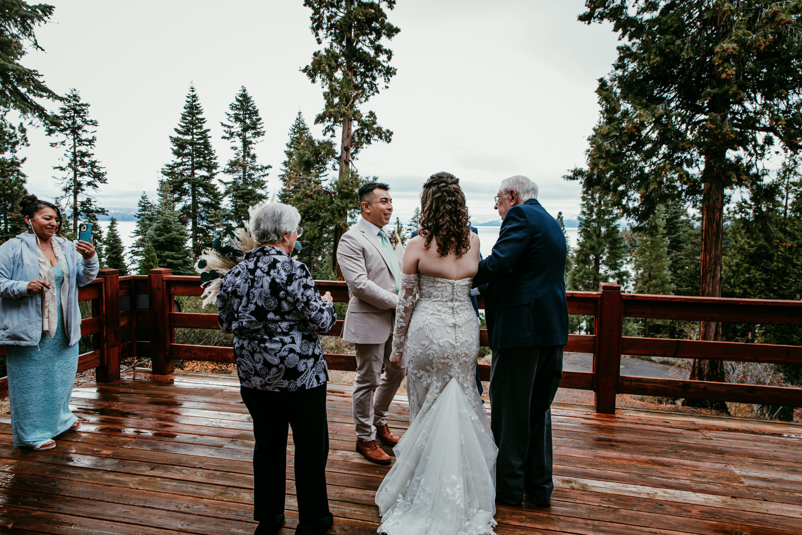 Couple exchanging vows on a wooden deck overlooking Lake Tahoe during their October Airbnb elopement ceremony.