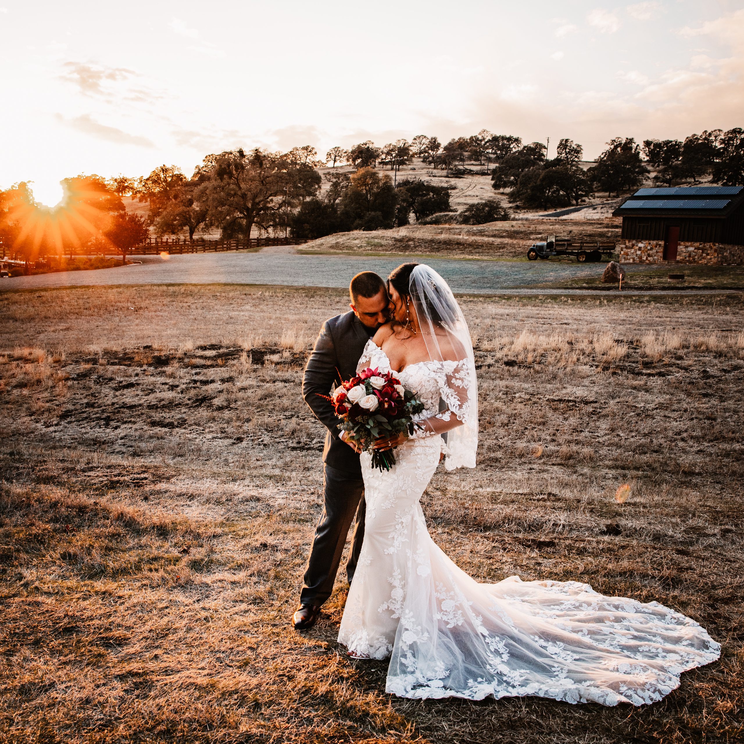 Newlyweds embracing in a golden field at sunset at Rancho Victoria in Plymouth, California.