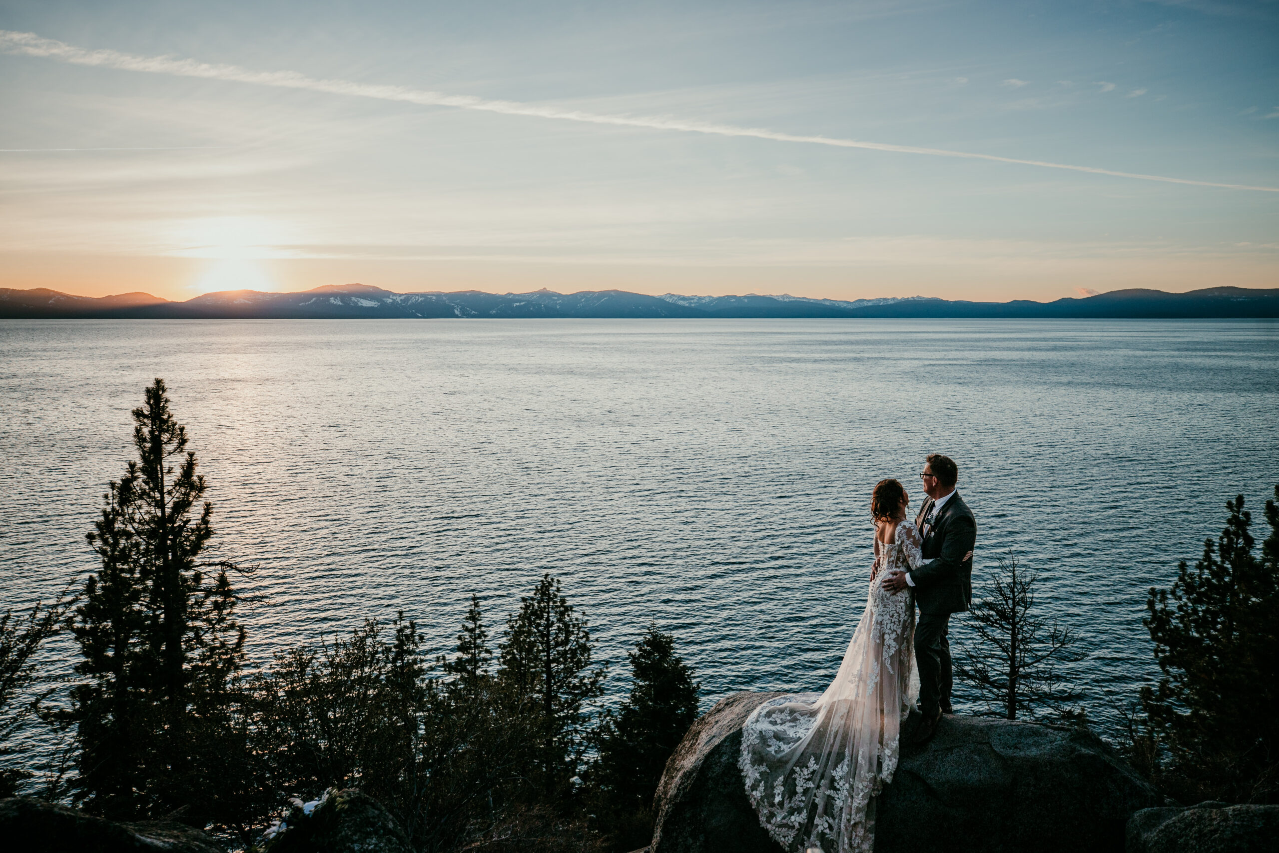 Couple standing on cliff above Lake Tahoe at sunset, romantic national park style elopement