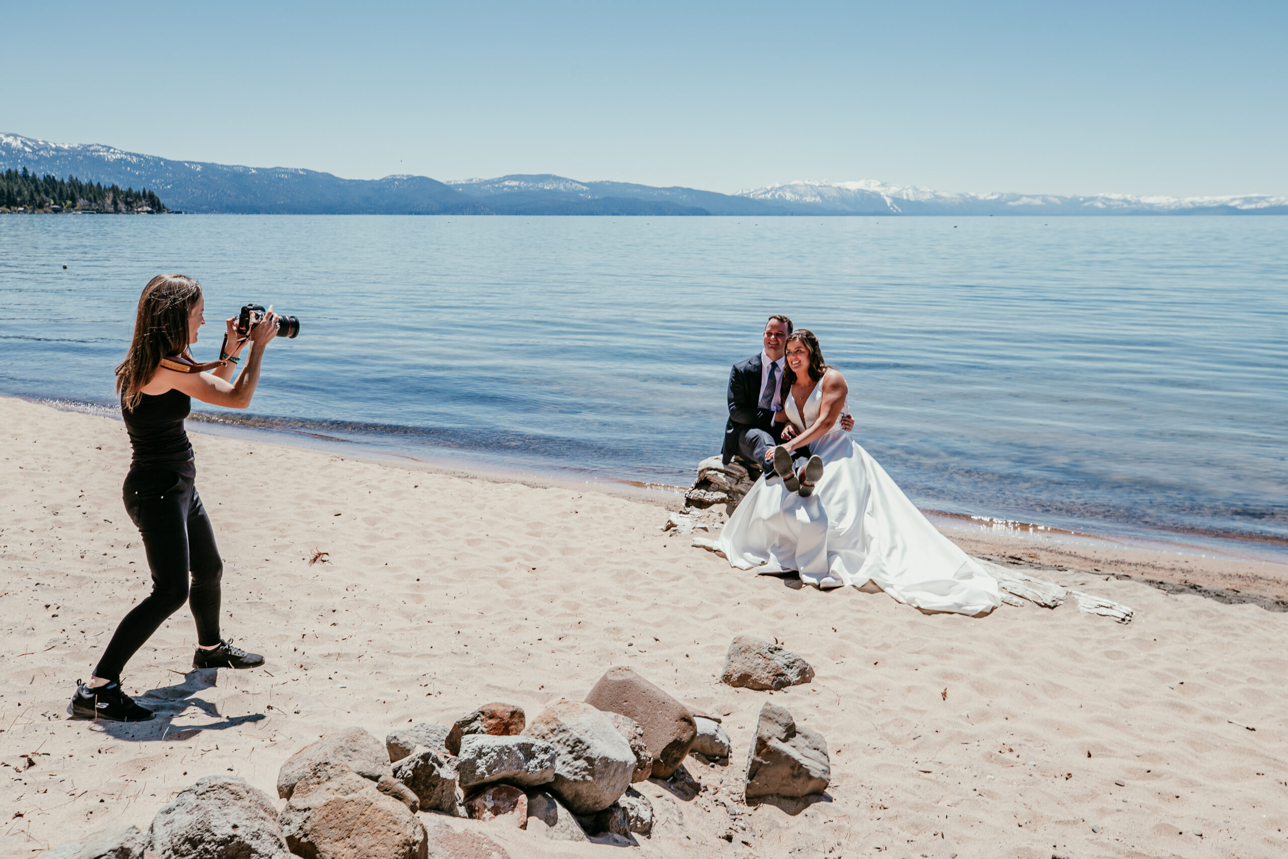 Elopement photographer photographing a couple sitting together on the sandy beach during a Lake Tahoe elopement.