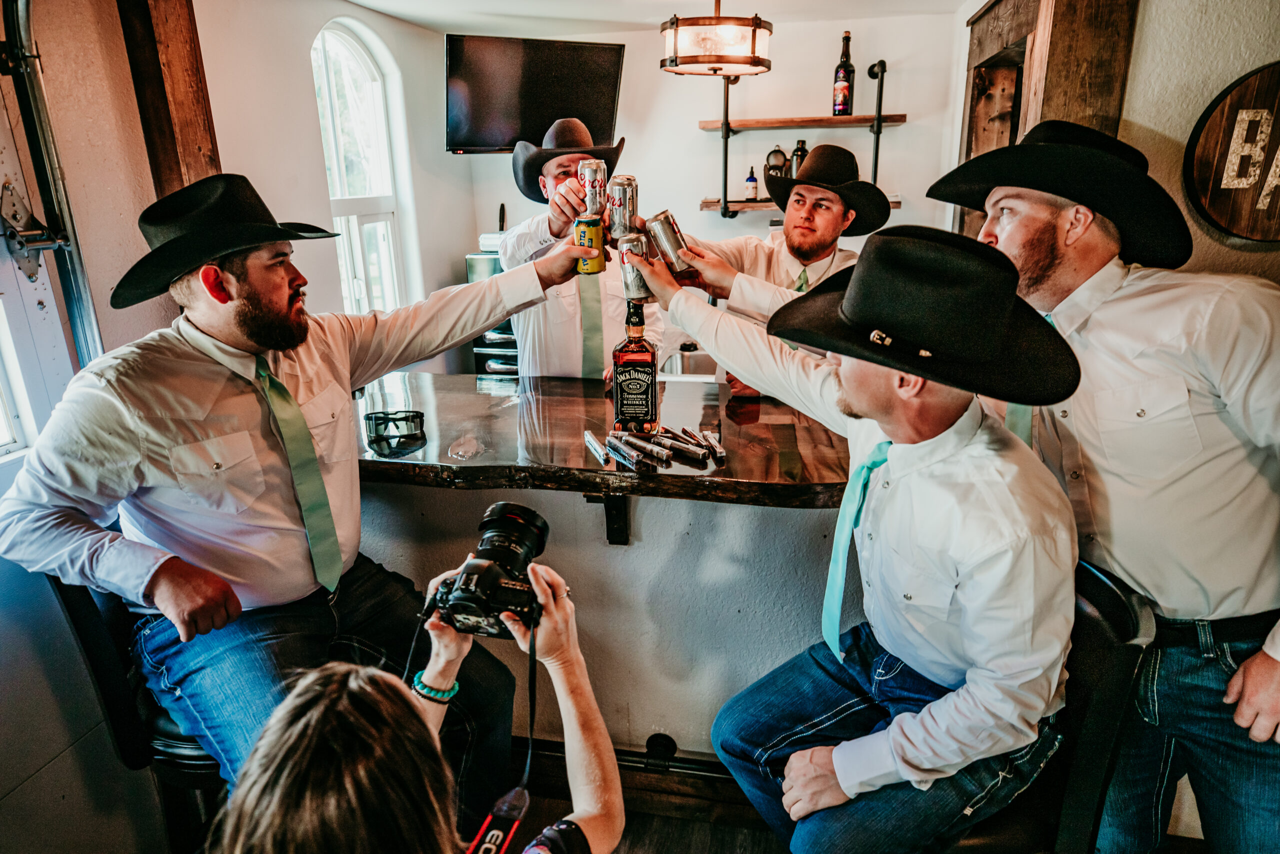 Elopement photographer documenting candid moments as groomsmen toast drinks during wedding preparations.
