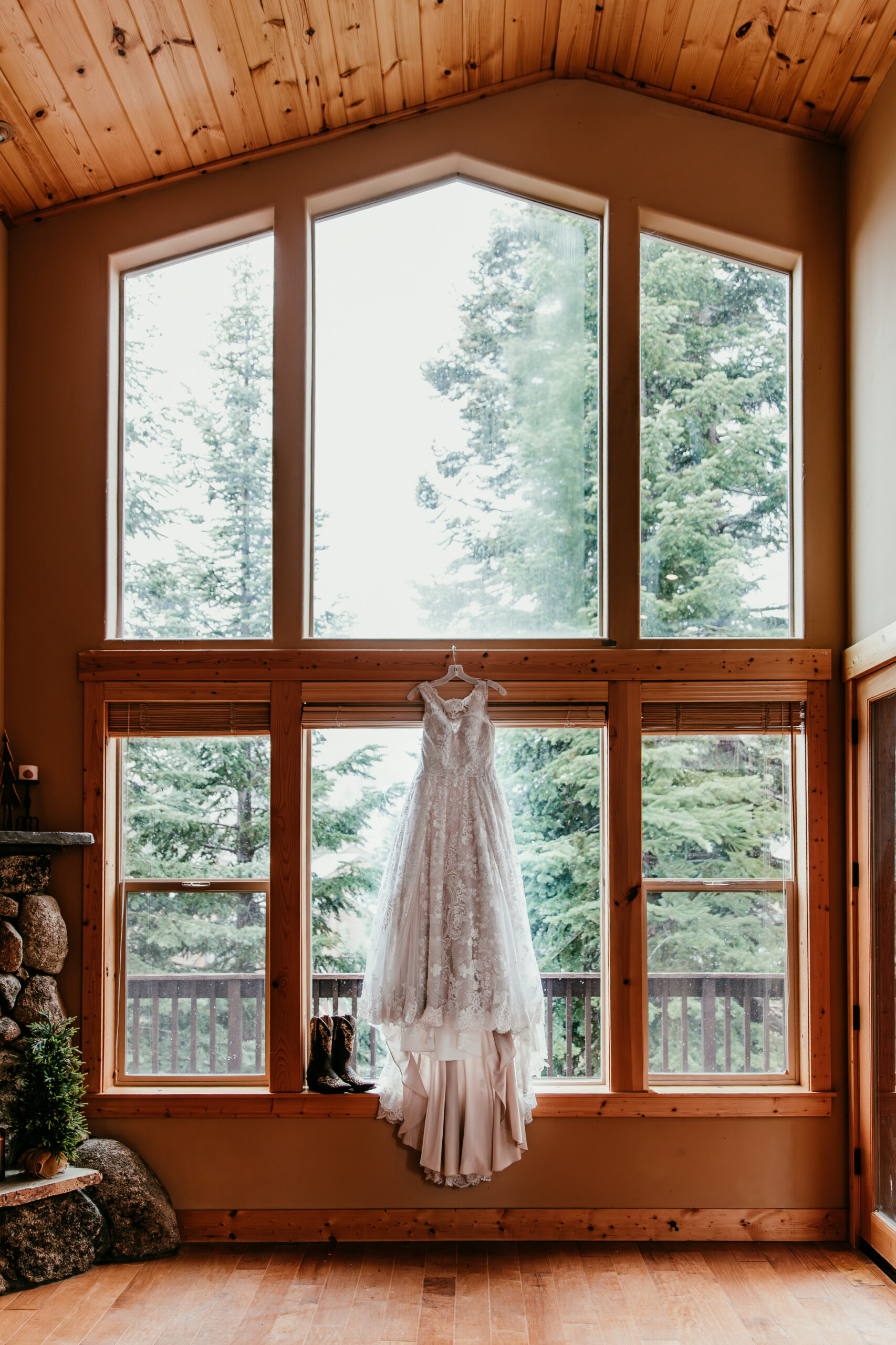 Wedding dress hanging in a cozy mountain cabin window showing intimate elopement ideas in California