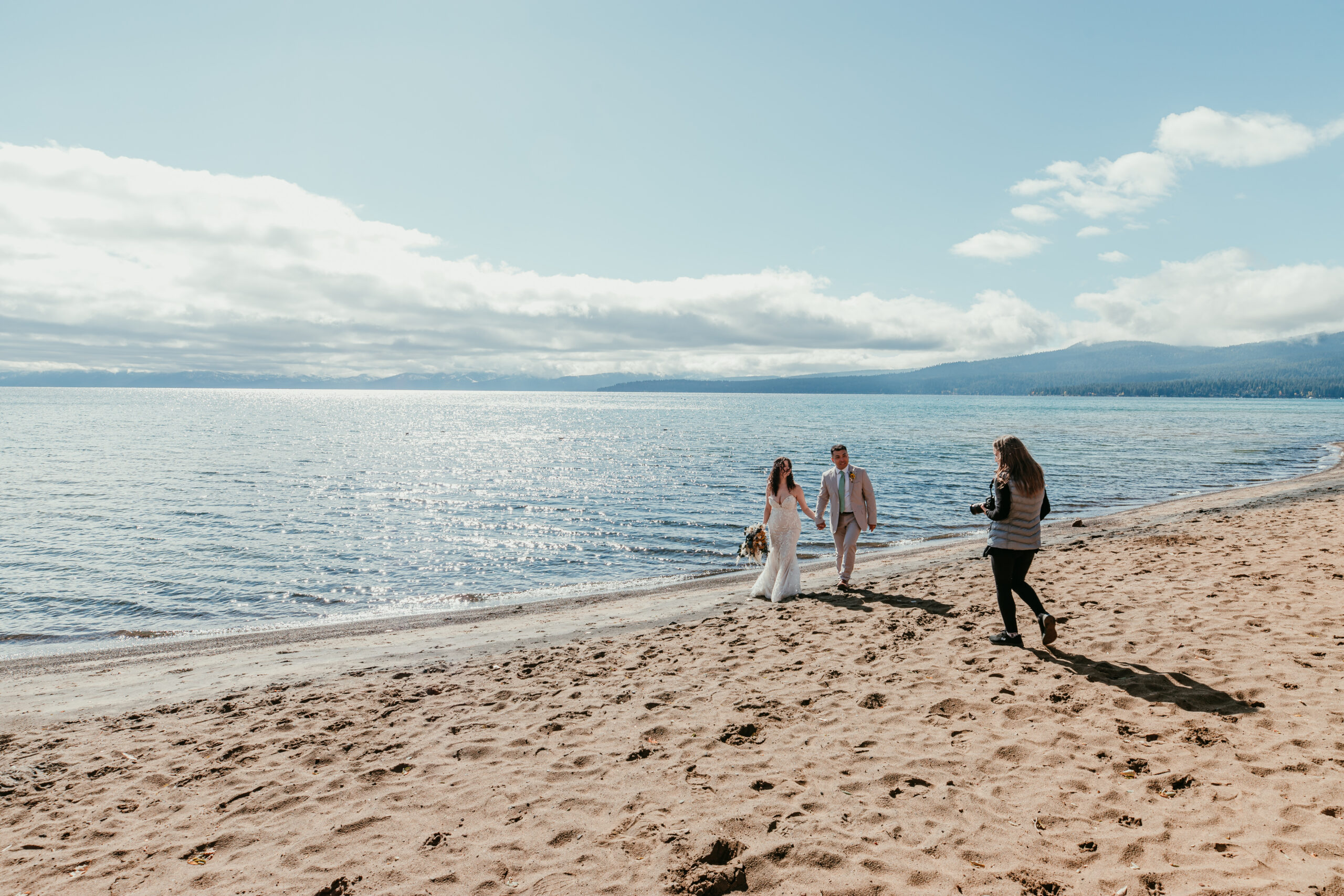 Elopement photographer photographing a newly married couple walking along the Lake Tahoe shoreline after their ceremony.