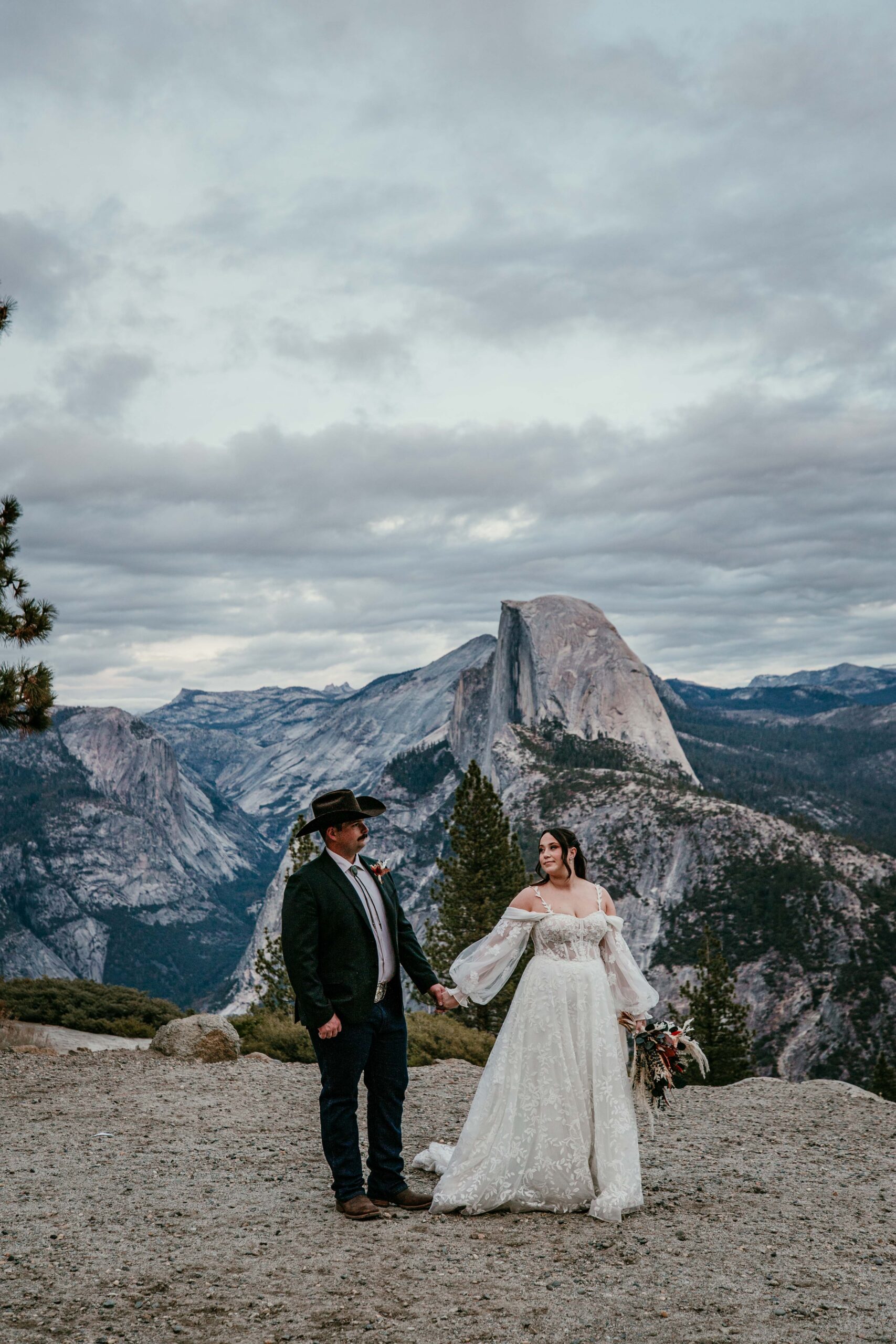 Bride and groom standing together at Yosemite cliffside overlook, romantic national park elopement inspiration