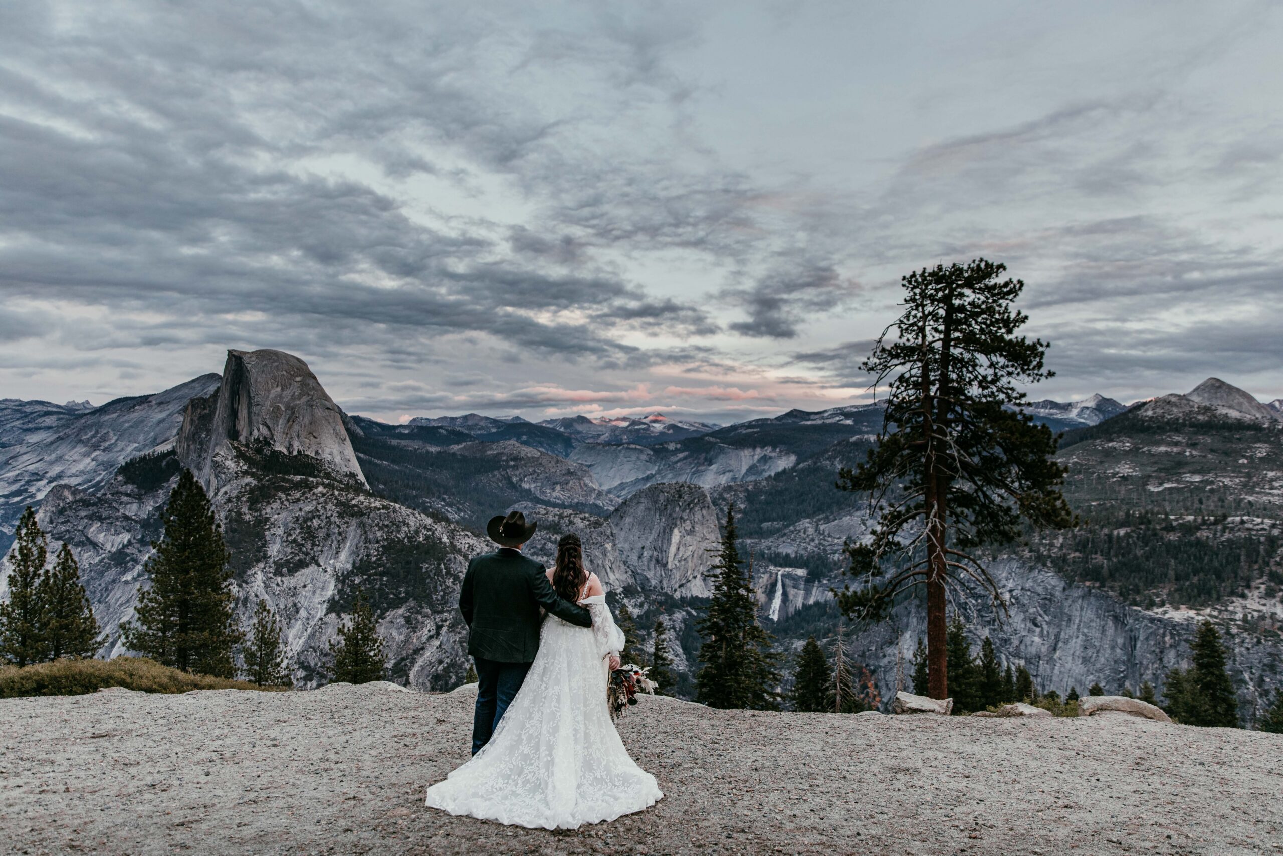 Couple overlooking Yosemite at sunset after their small wedding ceremony, epic mountain views and moody sky