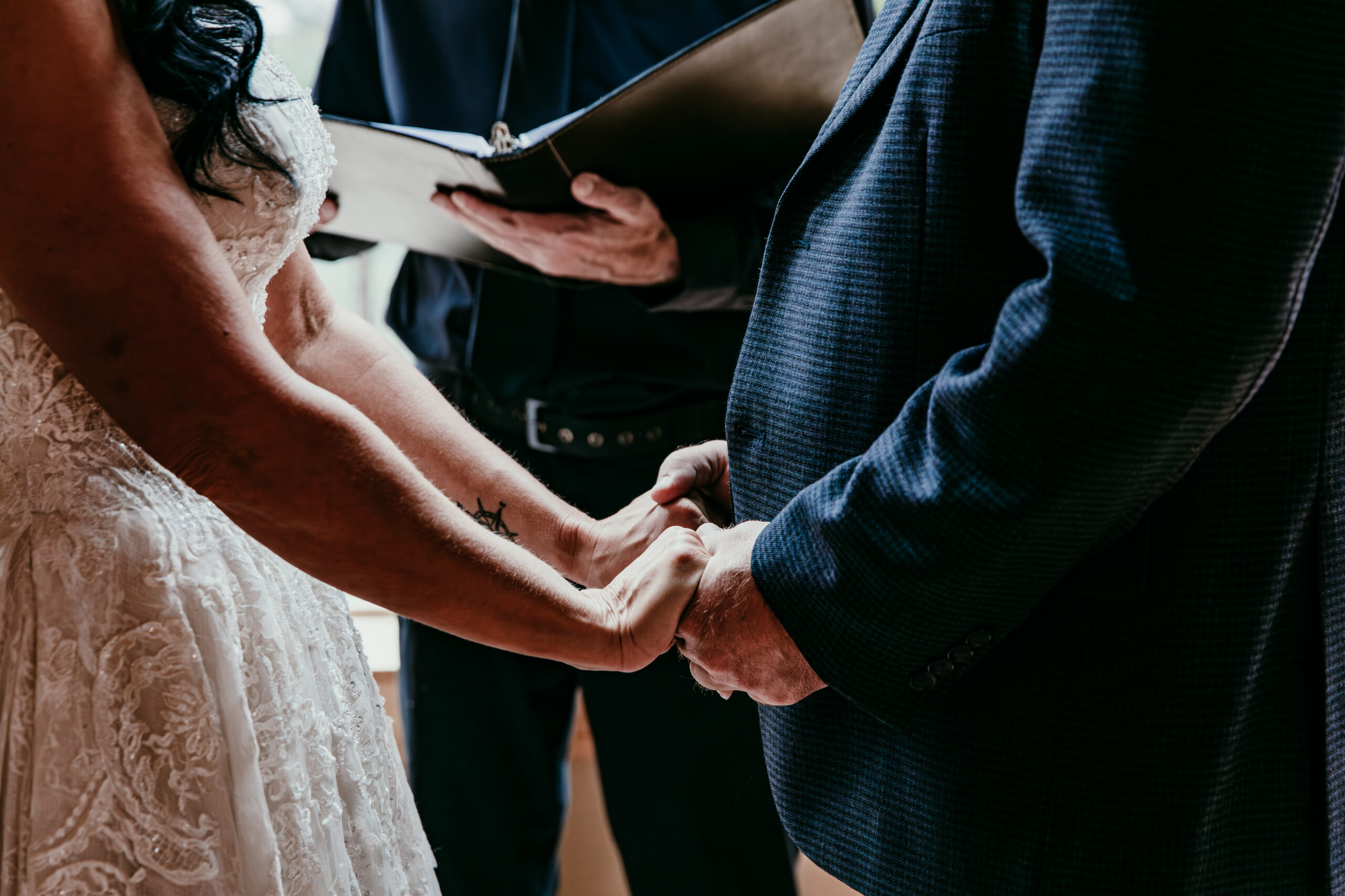 Close-up of couple holding hands during an intimate small wedding ceremony, emotional vow exchange moment