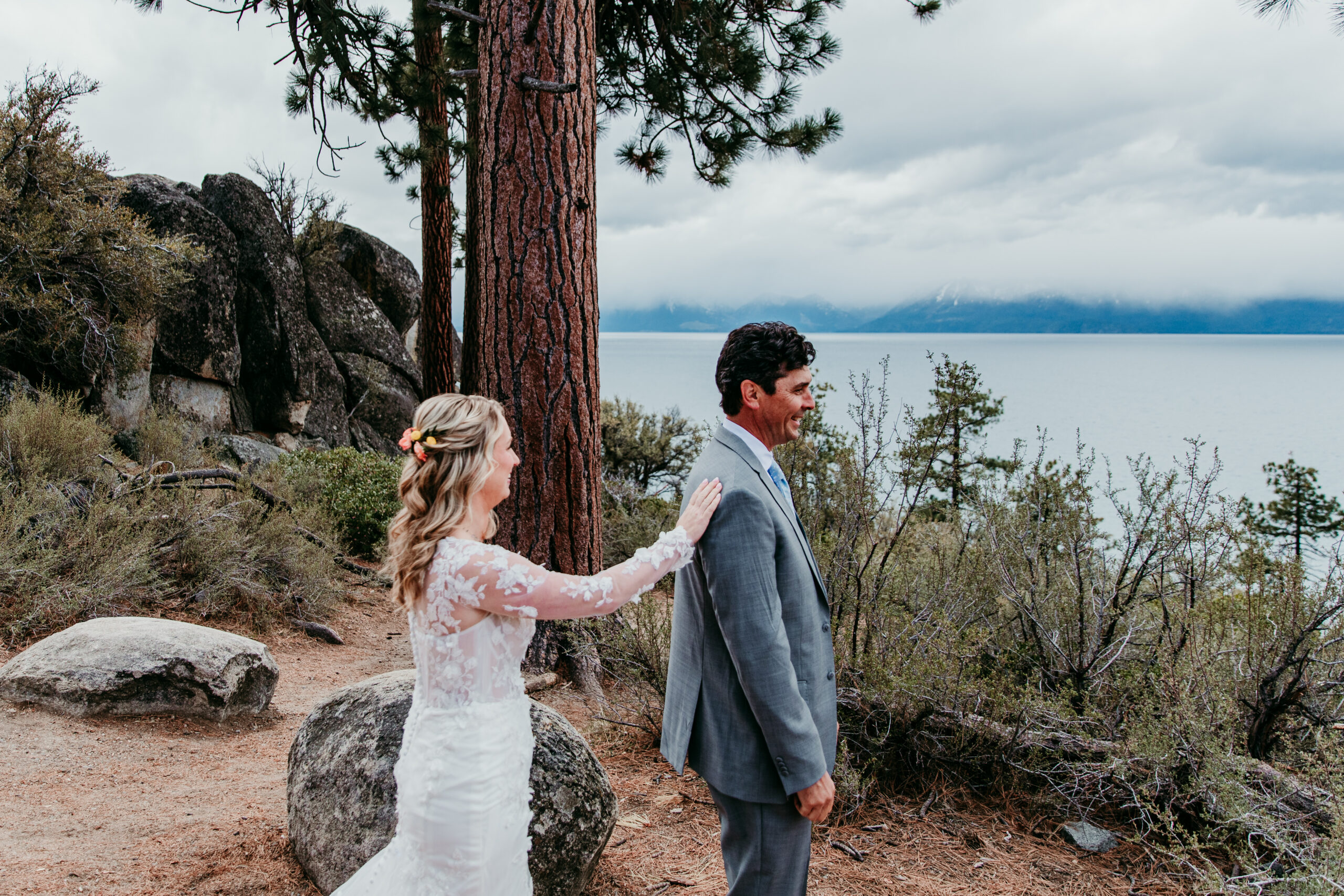 Bride tapping the groom on the shoulder before their first look during a rainy Lake Tahoe elopement at Logan Shoals Vista Point.