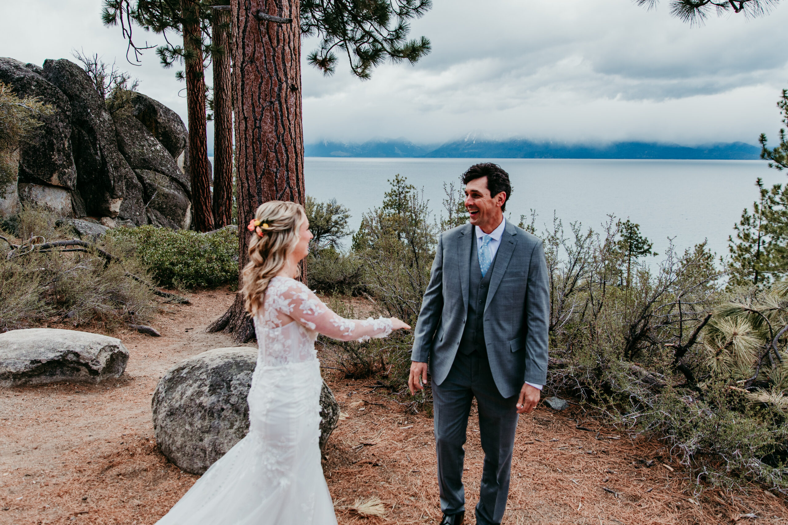 Groom smiling as he turns around to see his bride for their first look during a rainy Lake Tahoe elopement overlooking Lake Tahoe.