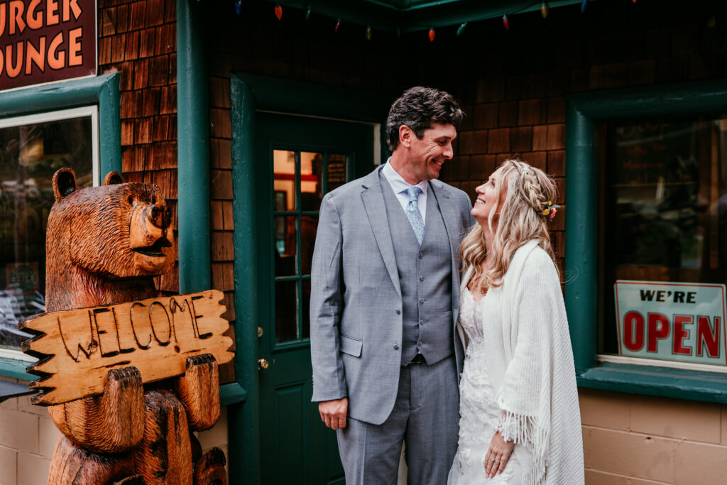 Bride and groom smiling outside Burger Lounge during their rainy Lake Tahoe elopement while taking a break to warm up.