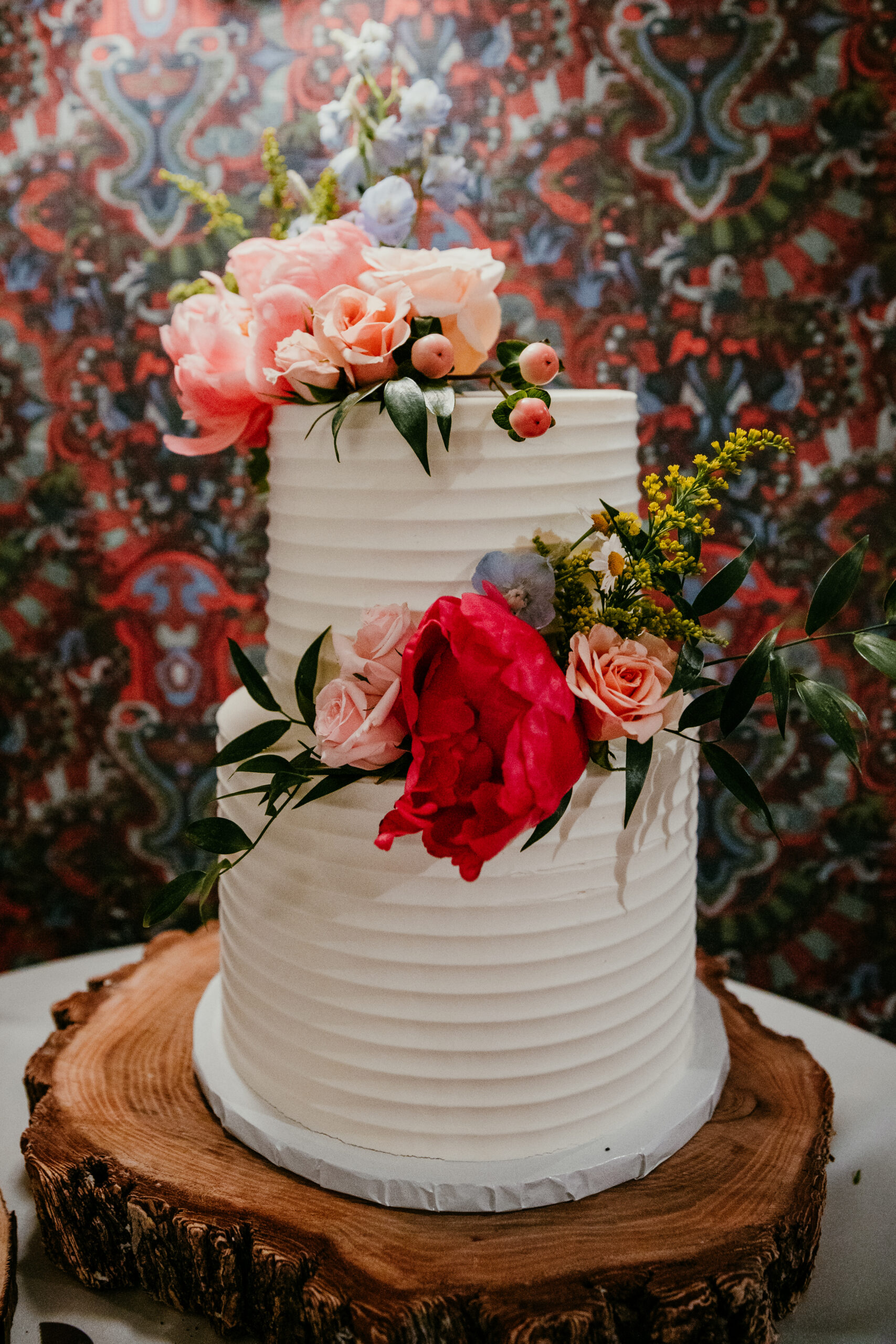 Small wedding cake decorated with colorful fresh flowers at The Landing reception following a rainy Lake Tahoe elopement.