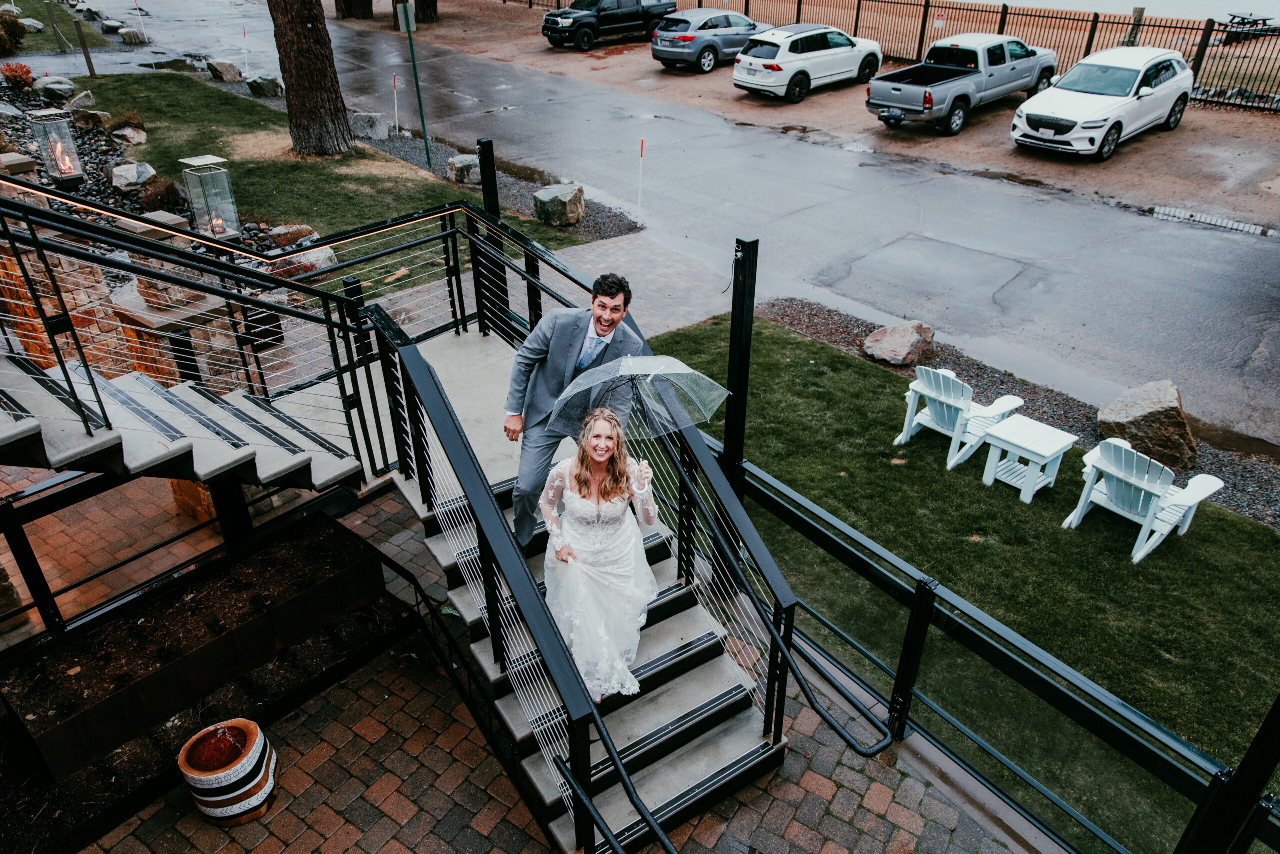 Bride and groom walking up the stairs at The Landing Resort after their rainy Lake Tahoe elopement, carrying a clear umbrella as they head to their reception.
