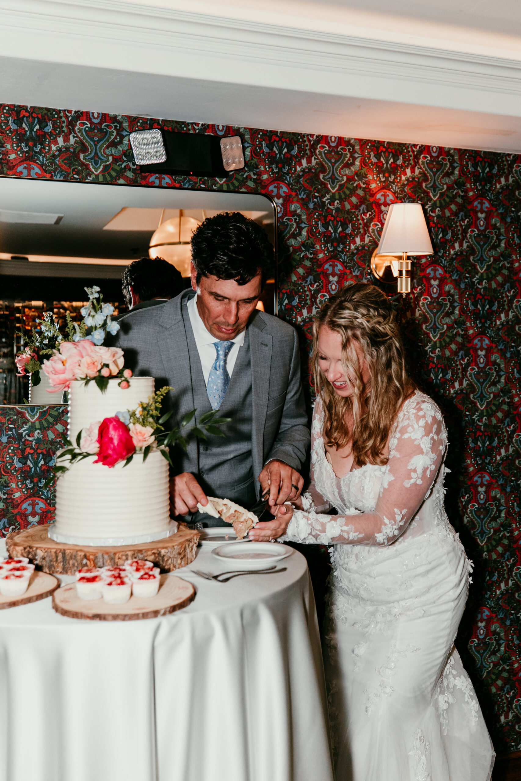 Bride and groom laughing together as they serve wedding cake during their reception after a rainy Lake Tahoe elopement at The Landing Resort.
