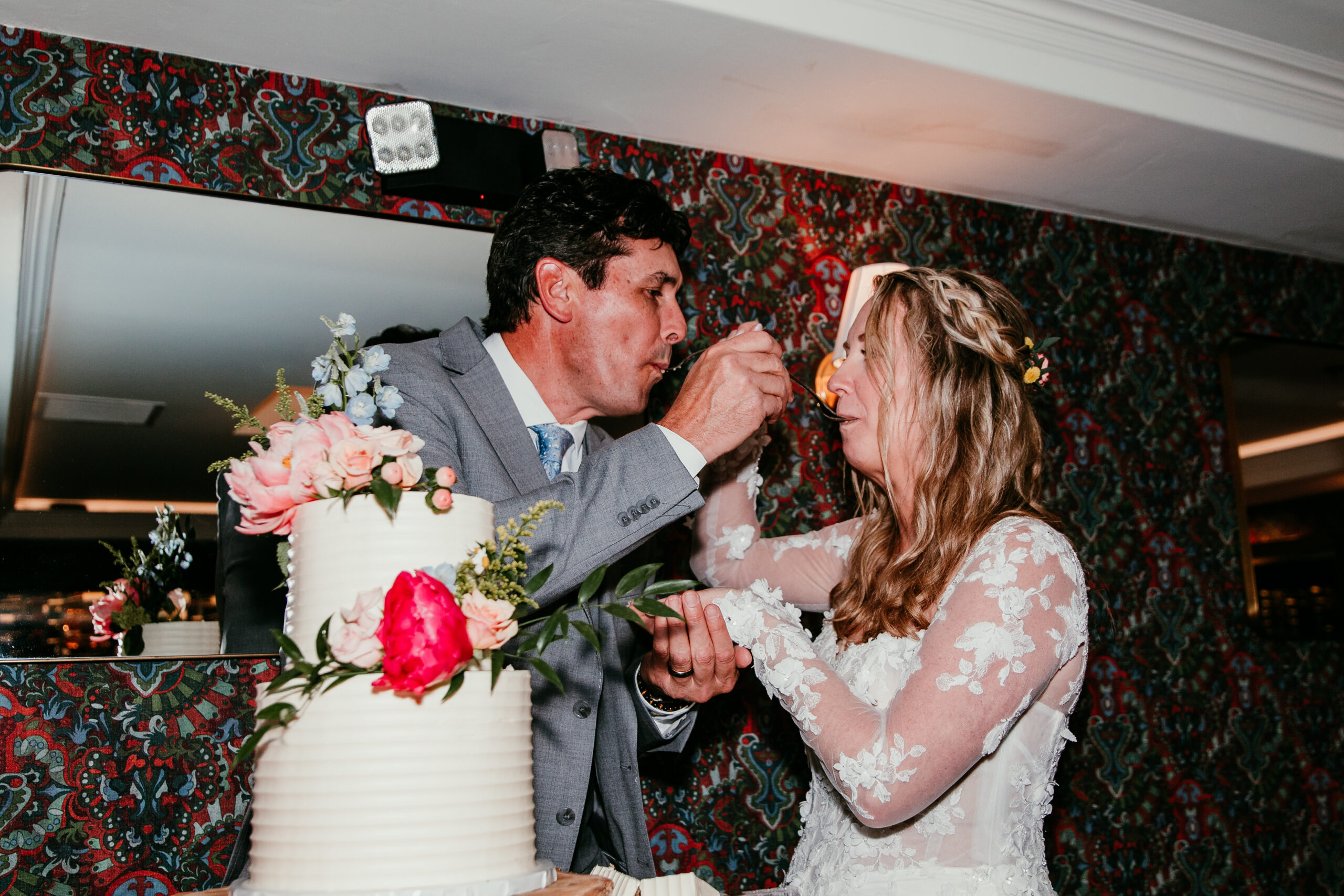 Bride and groom feeding each other wedding cake during their reception after a rainy Lake Tahoe elopement at The Landing Resort.