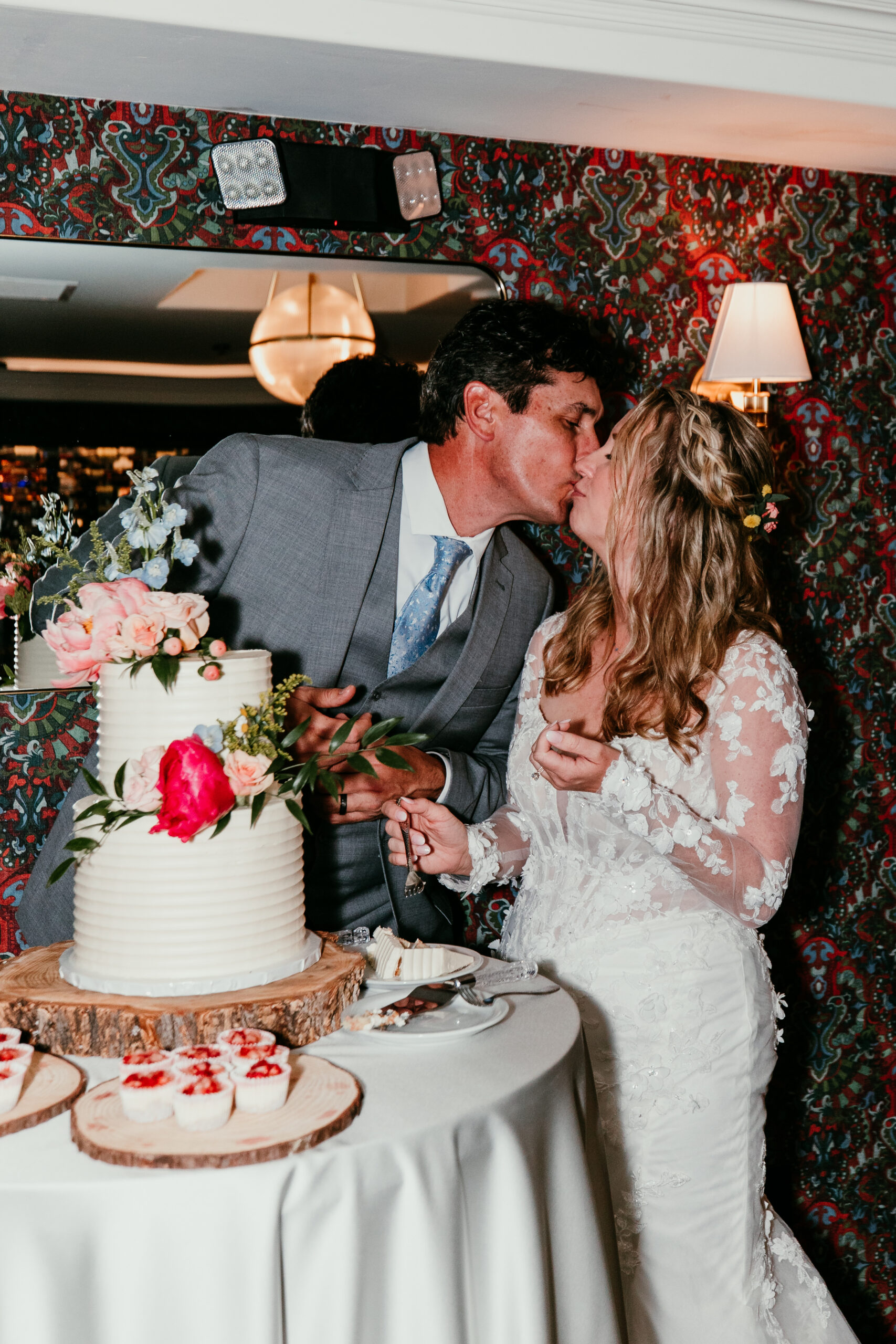 Bride and groom sharing a kiss after cutting their wedding cake during the reception following their rainy Lake Tahoe elopement at The Landing Resort.