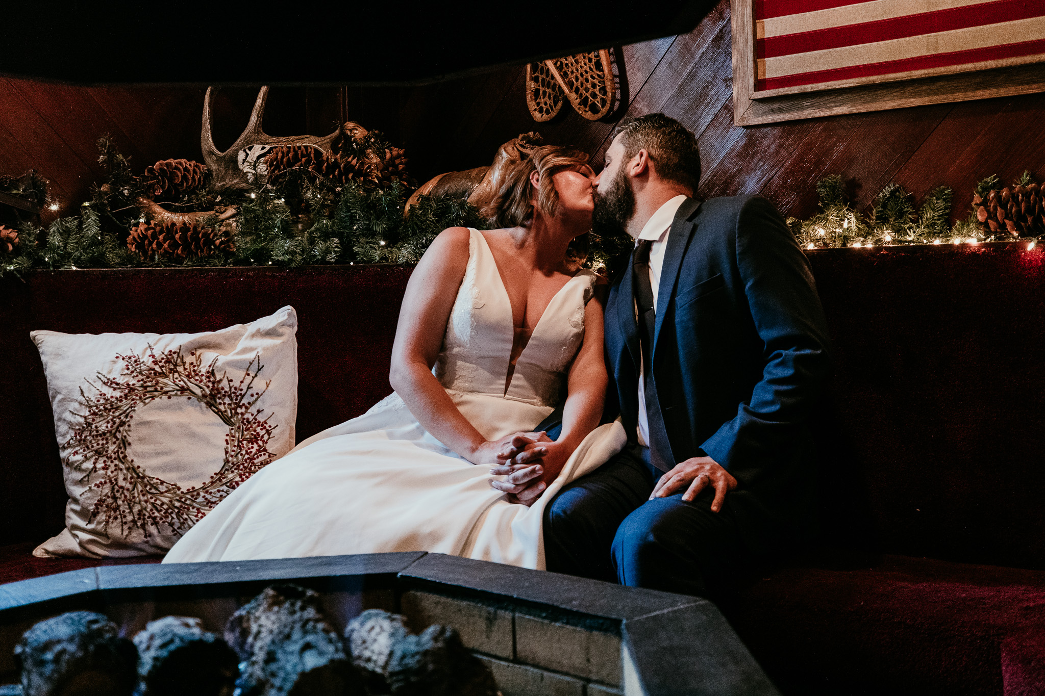 SJ and Dave kissing while seated together on a cushioned bench after their forest ceremony.