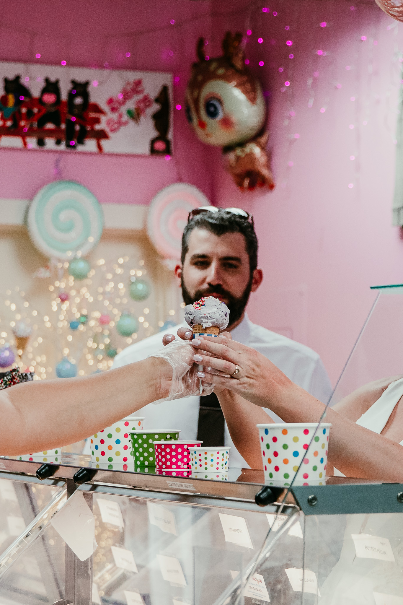 Dave holding an ice cream cone inside a colorful pink ice cream shop.