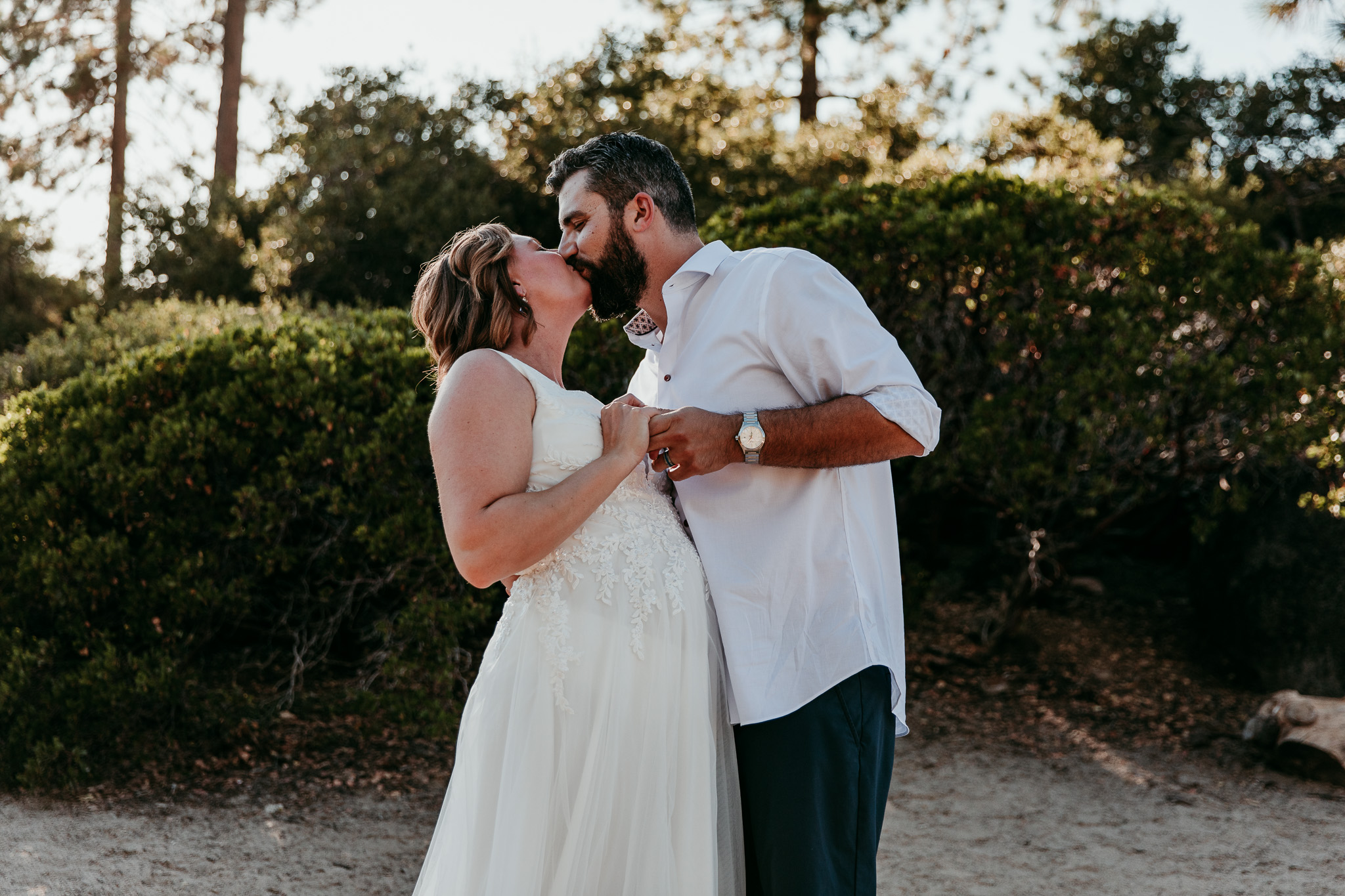 SJ and Dave kissing during their first dance, surrounded by trees and greenery.