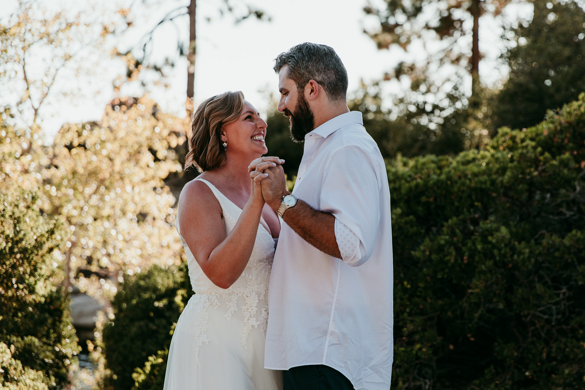 SJ laughing with Dave as they hold hands during their outdoor first dance at Lake Tahoe.