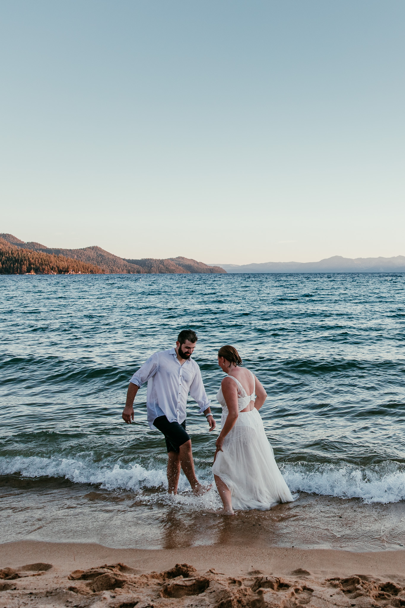 SJ and Dave walking out of Lake Tahoe together in their soaked wedding clothes.