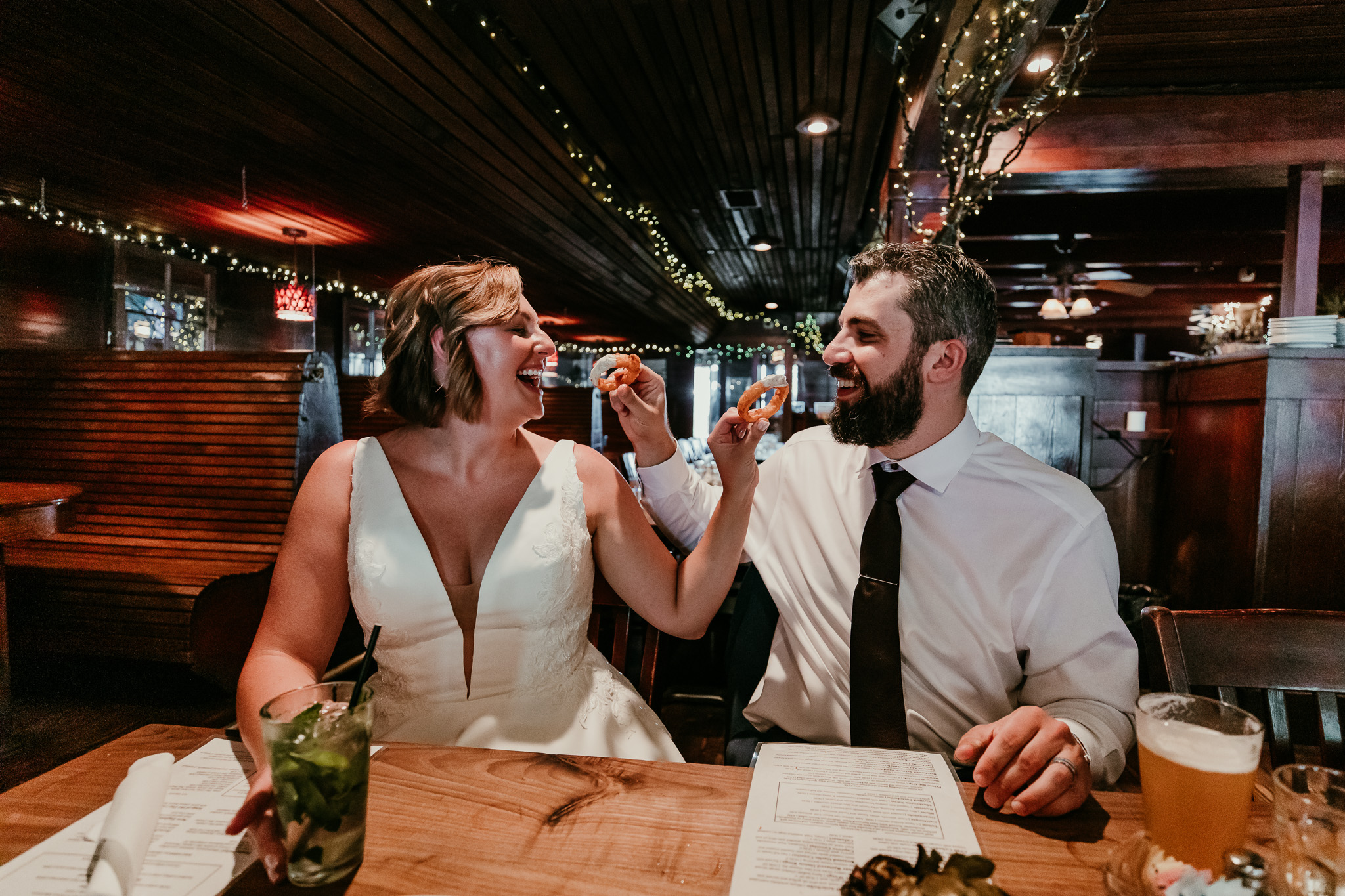 SJ and Dave laughing together at a restaurant table during their summer Lake Tahoe elopement.